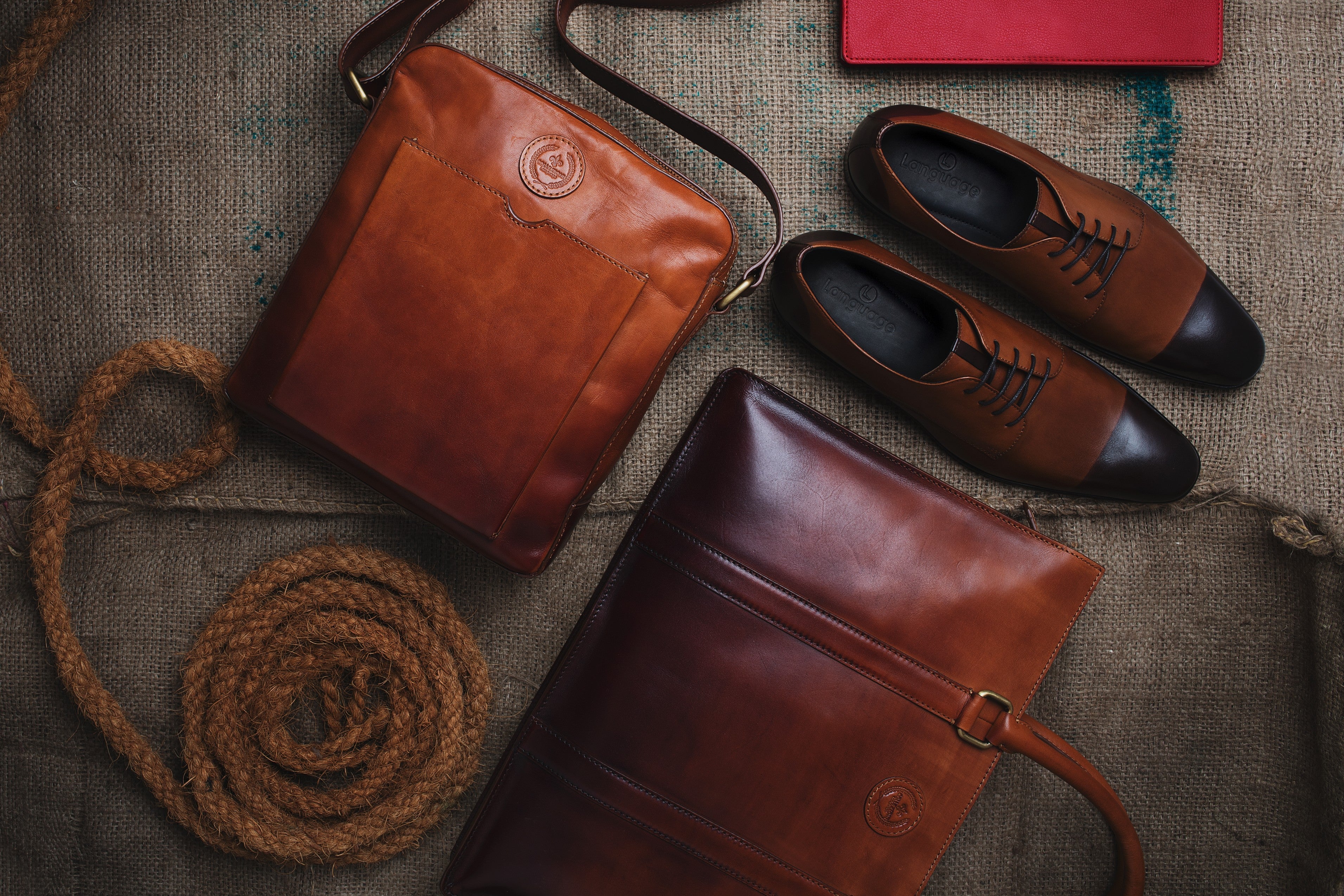 Brown leather bags and men's oxford shoes on rustic fabric background