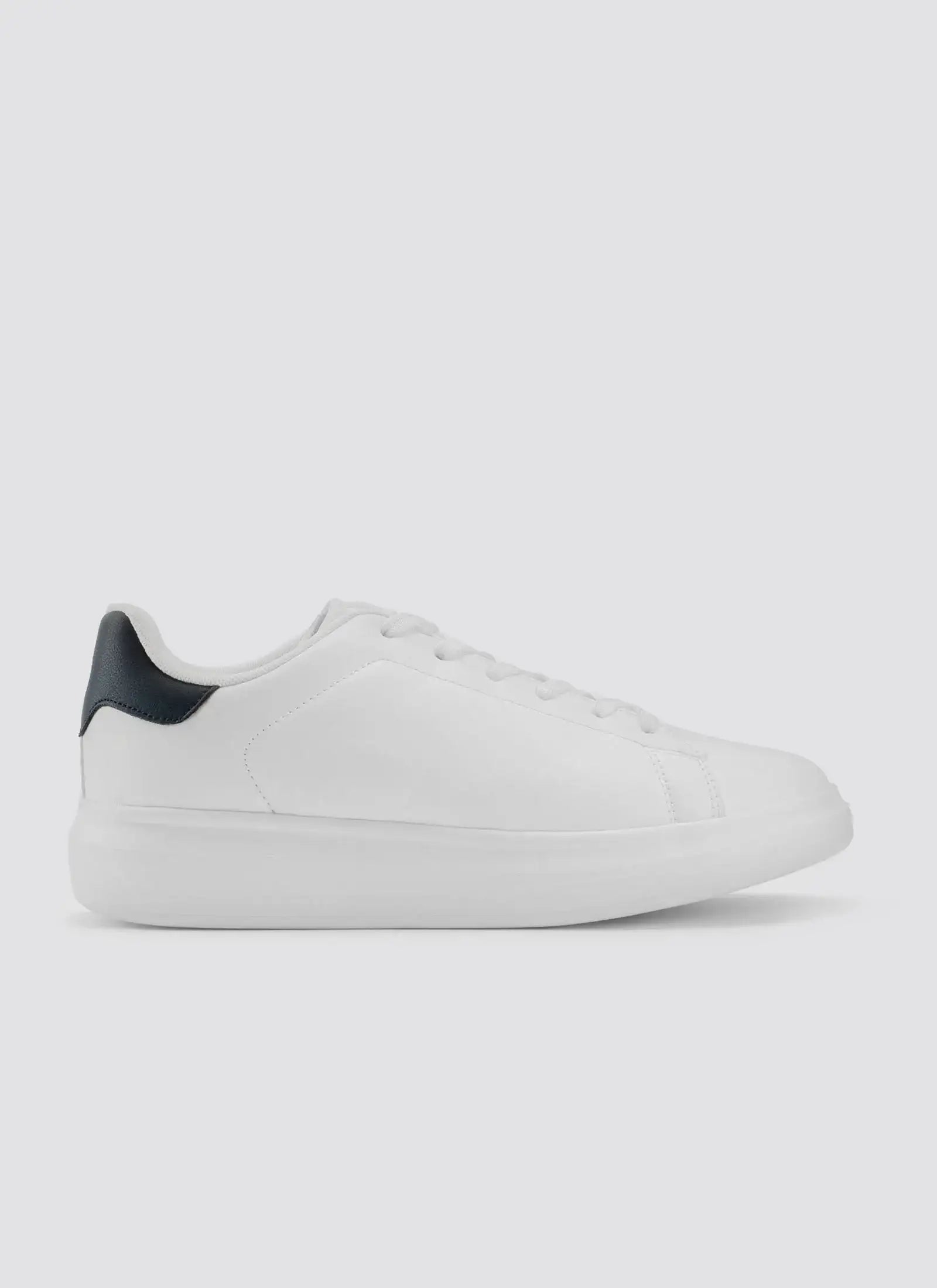 White leather sneaker with black heel accent, minimal lace-up design, side view on plain background