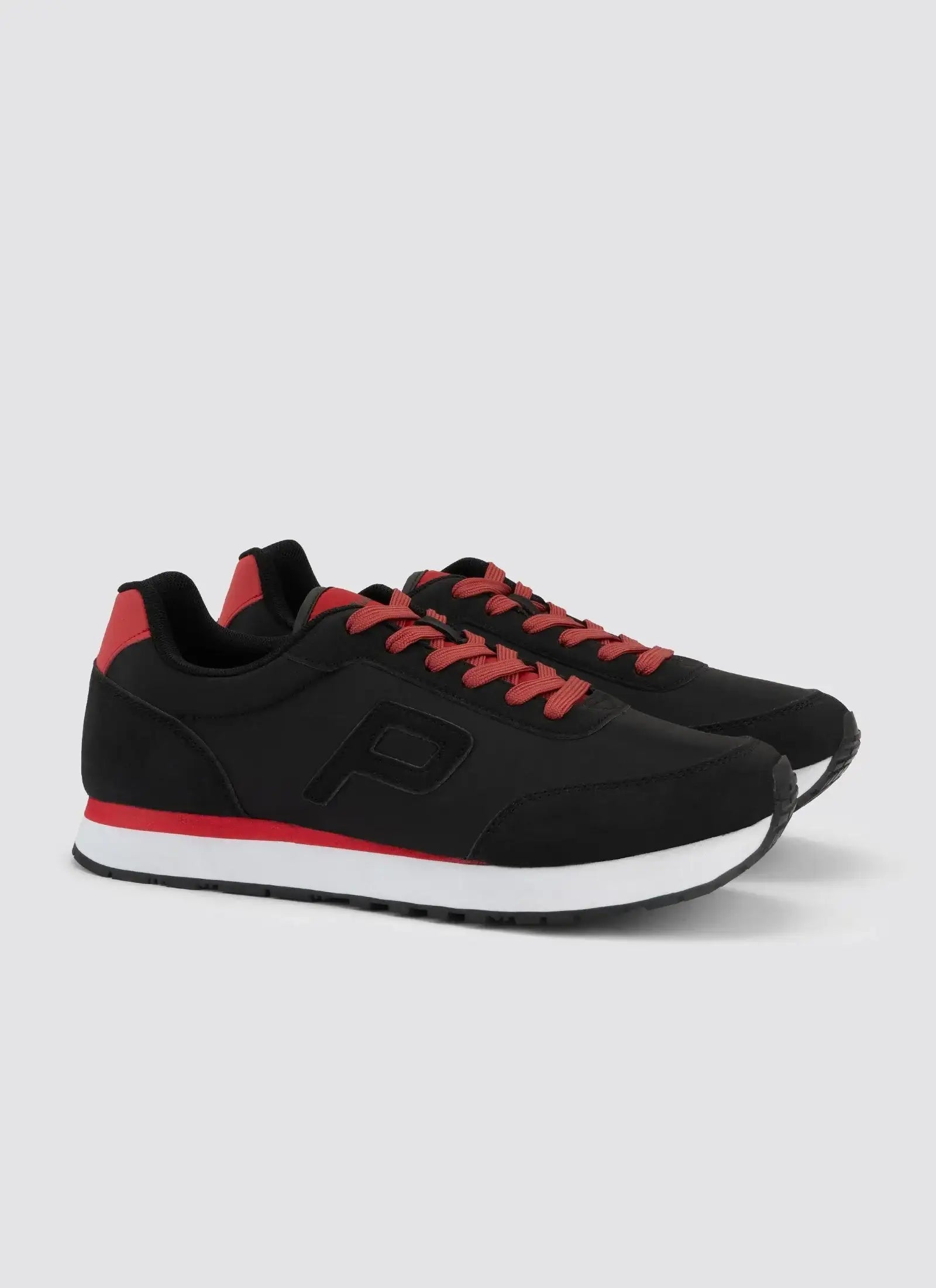 Black and red lace-up sneakers with white soles for men, side view on plain background