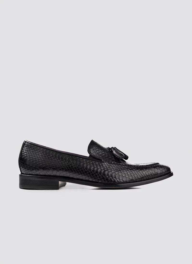 Black textured men's loafer with tassel detail and low heel on a plain background #color_black