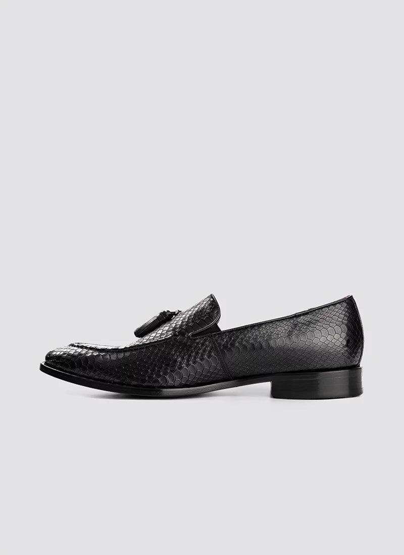 Black textured leather loafer with tassel detail for men, side profile on grey background