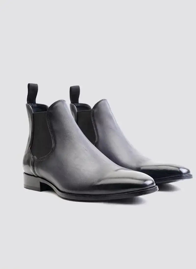 Men's black leather Chelsea boots with elastic side panels on a light background