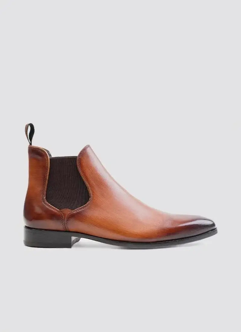 Tan leather Chelsea boot for men with elastic side panel and black sole on white background