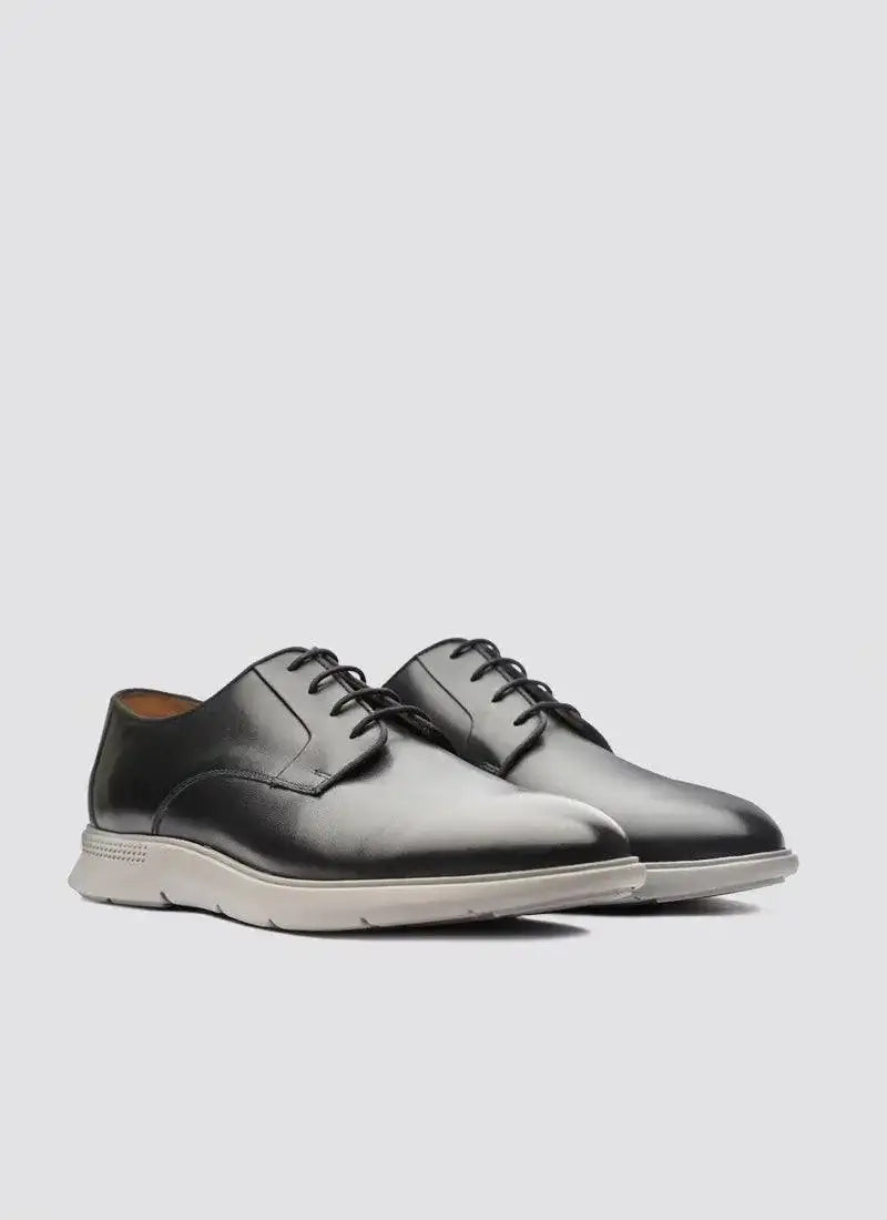 Men's black leather lace-up dress shoes with white soles on a light background
