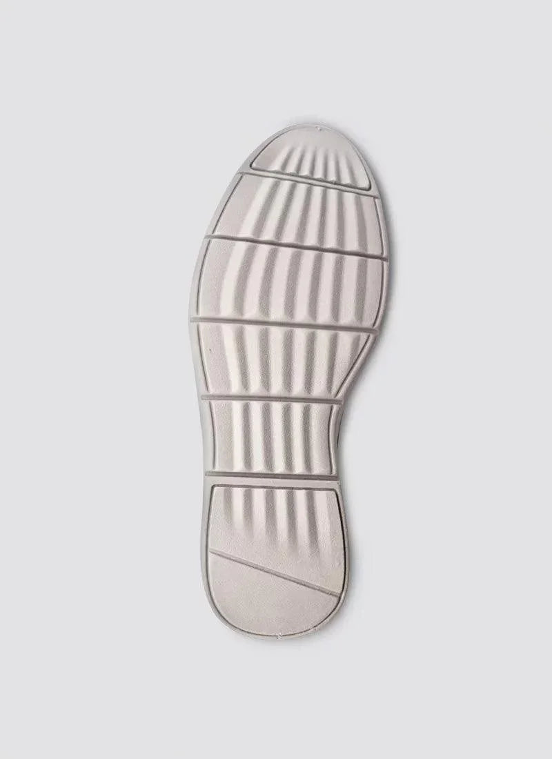 Textured rubber shoe sole with grooved grip pattern on a light grey background