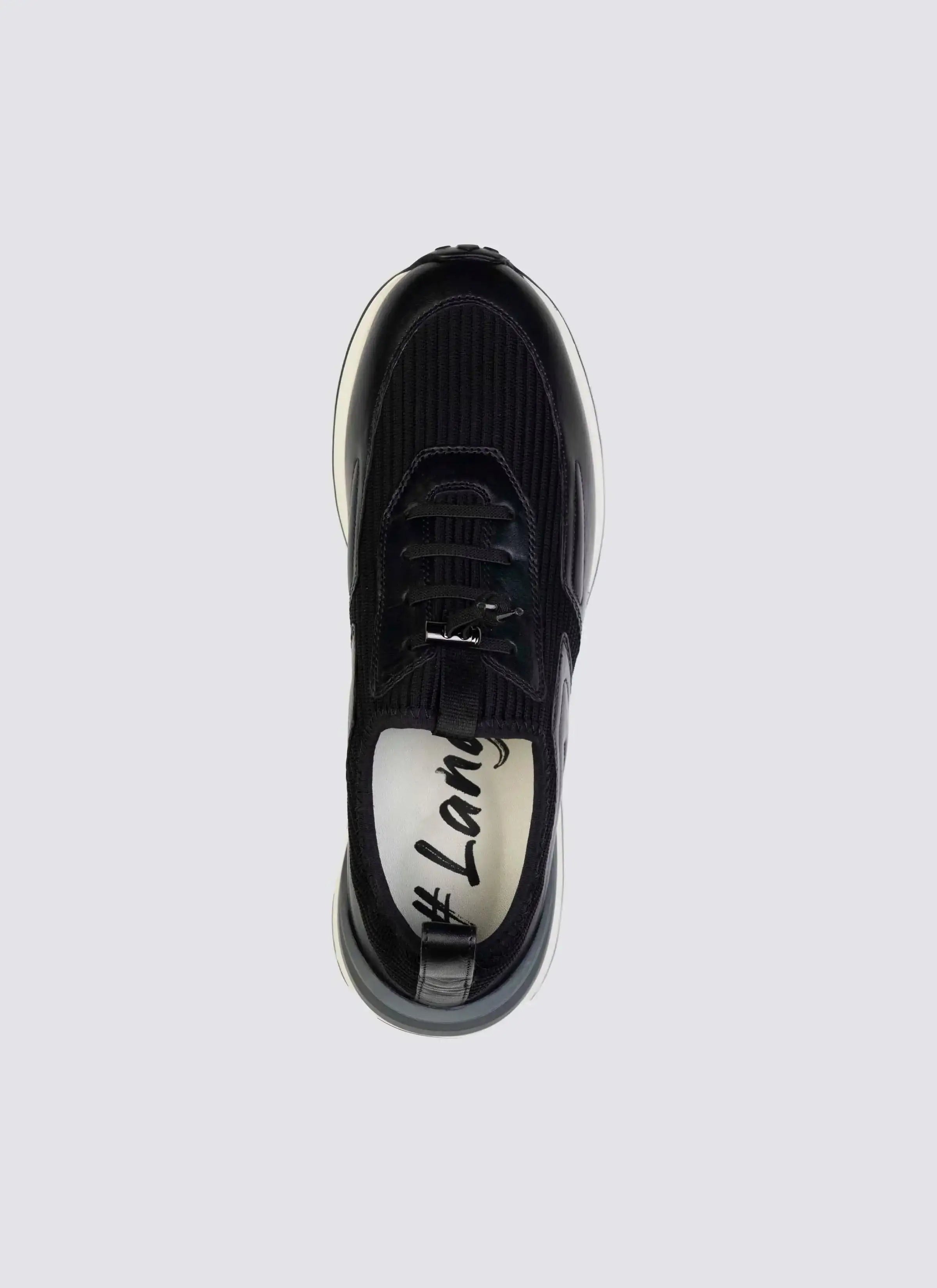 Top view of black sneaker with textured upper, lace-up closure, and white sole on plain background