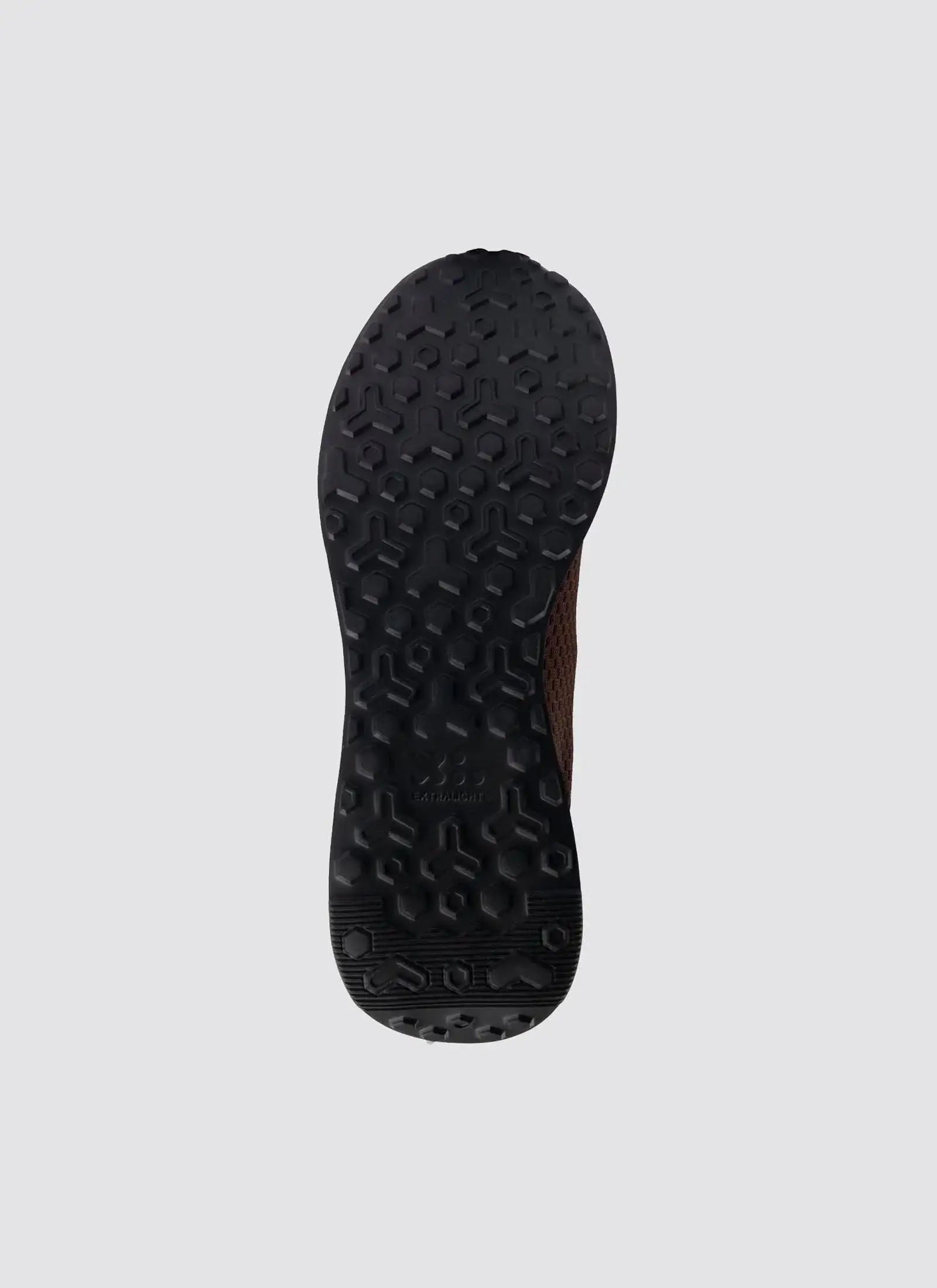 Close-up of black textured shoe sole with hexagonal grip, brown upper edge visible
