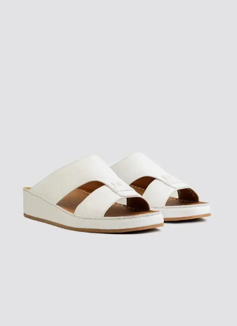 Pair of white leather slip-on sandals with crisscross straps and low wedge soles