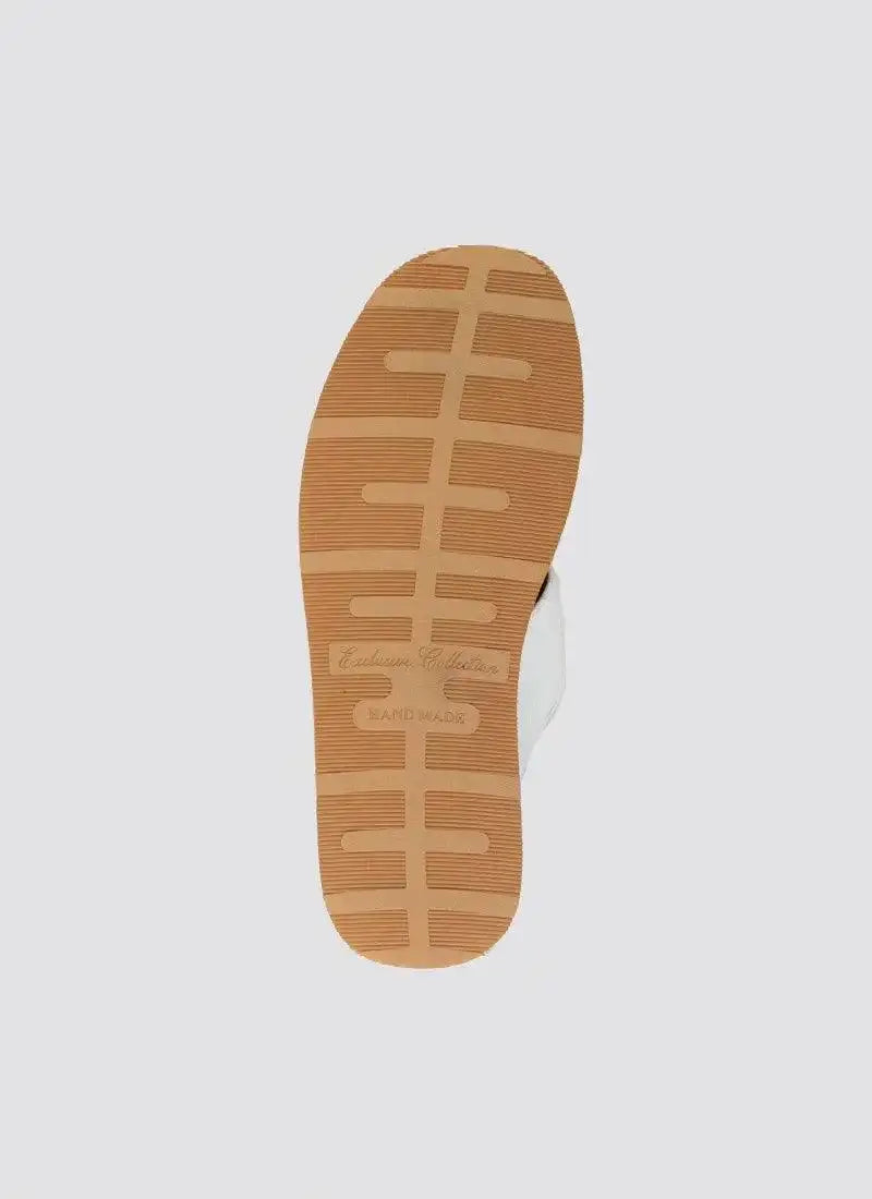 Close-up of tan rubber sole on white handmade loafer with textured grip pattern