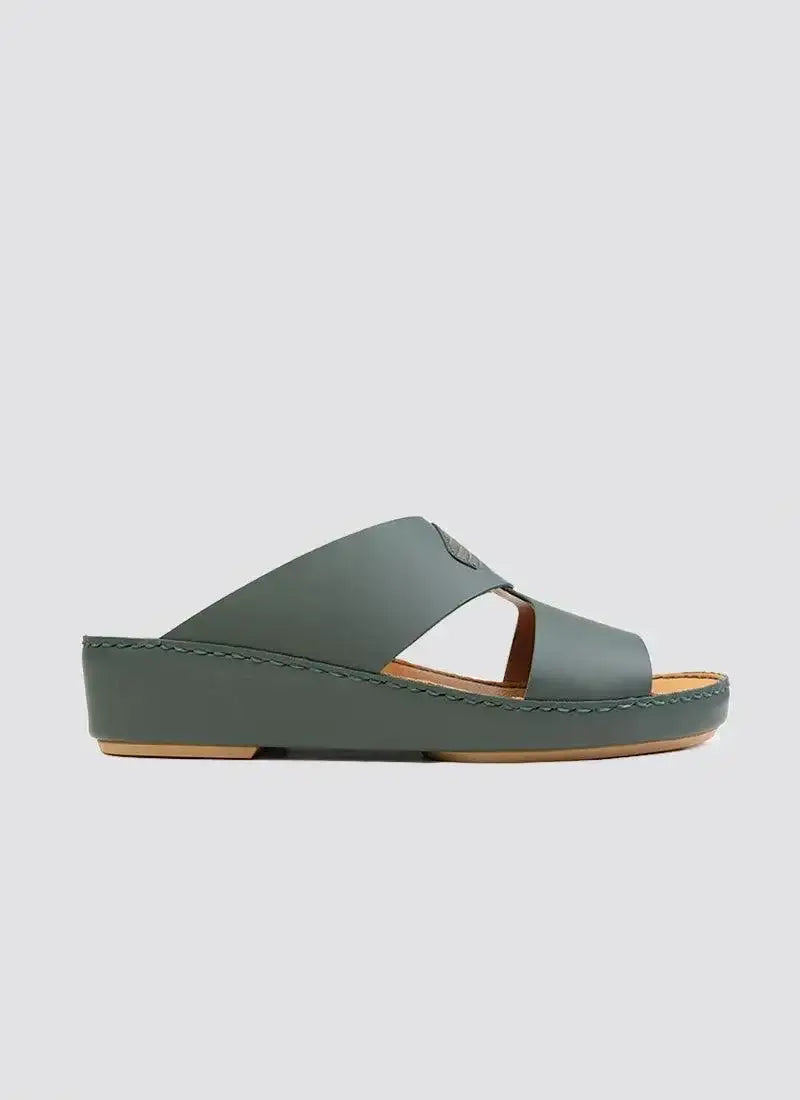 Green leather slide sandal with wedge heel and cross-strap design on white background