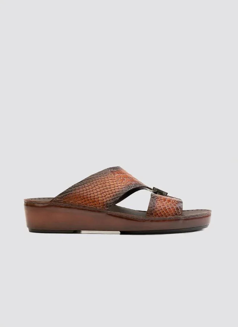 Brown slip-on sandal with textured, scale-like leather upper and wedge sole on white background