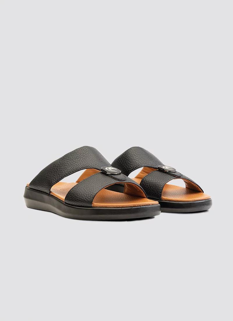 Black leather men's slip-on sandals with criss-cross straps and tan footbed on white background