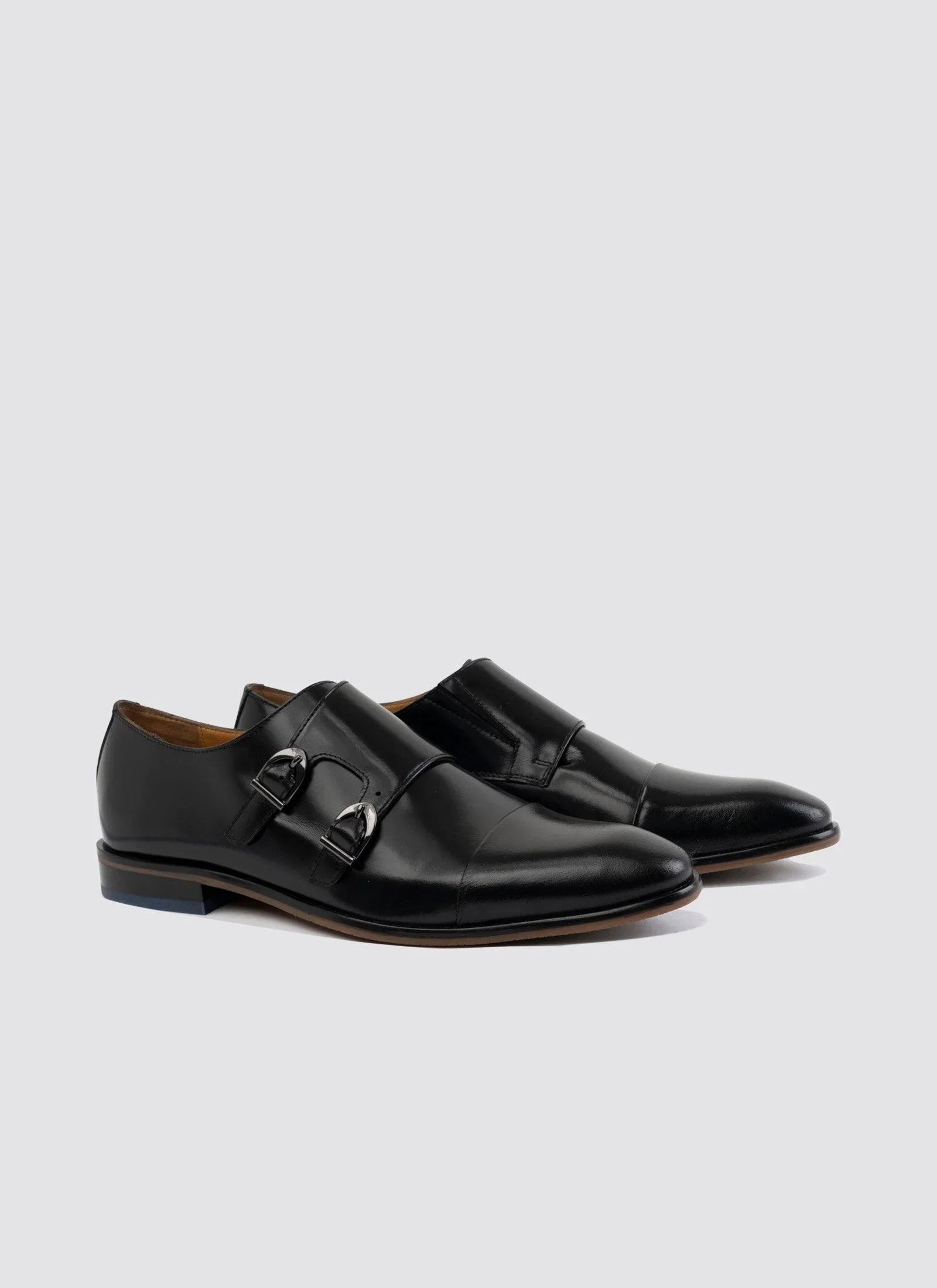 Black leather double monk strap dress shoes for men on a plain background