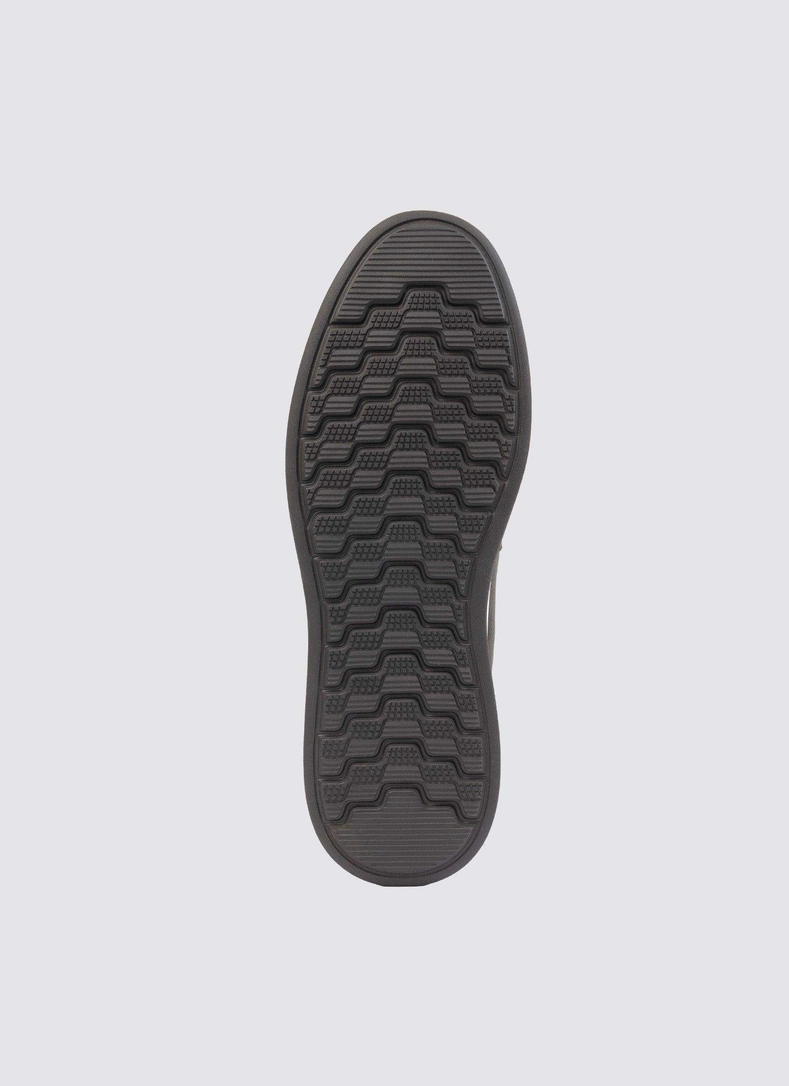 Black shoe sole with textured, non-slip rubber grip pattern on a light background