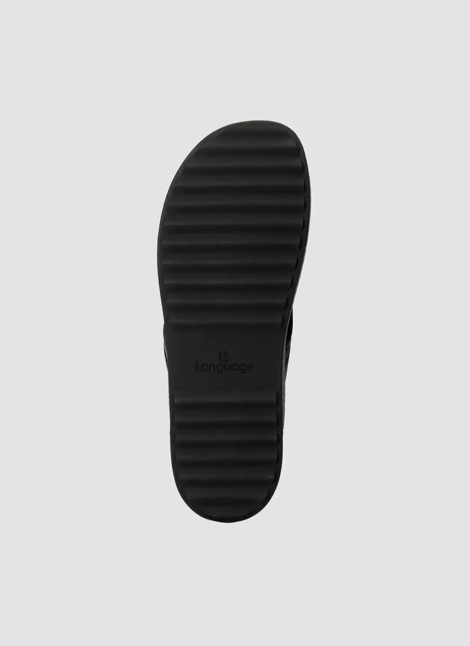 Black ridged rubber shoe sole with horizontal grooves on light background