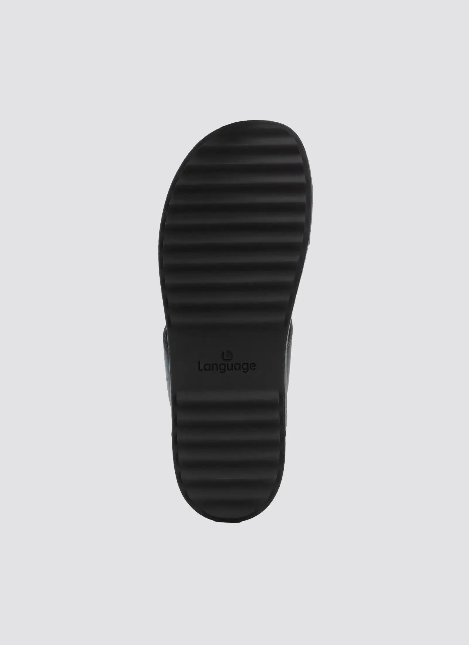 Textured black shoe sole with ridged grip pattern, photographed on a plain background.