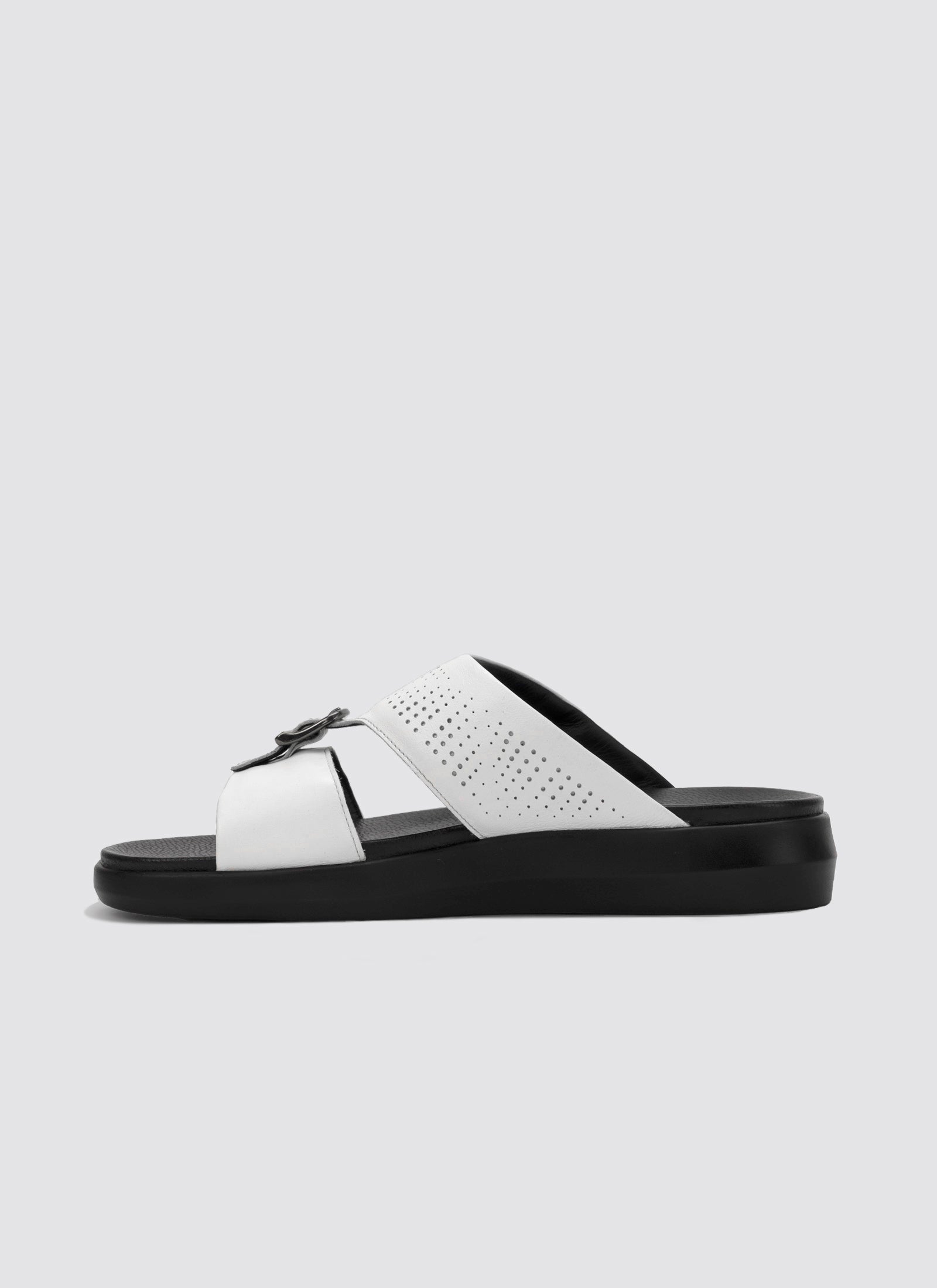 White sandal with black sole on a light gray background
