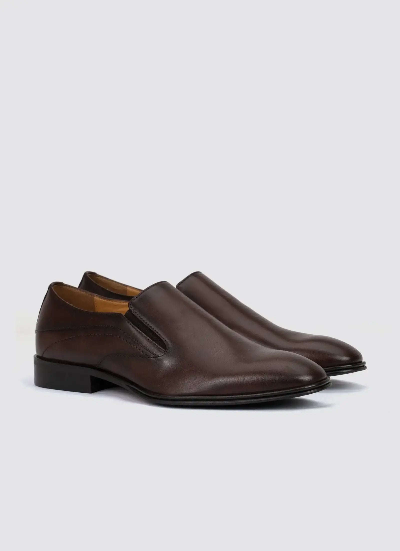 Men's brown leather slip-on dress shoes with low heel on light background