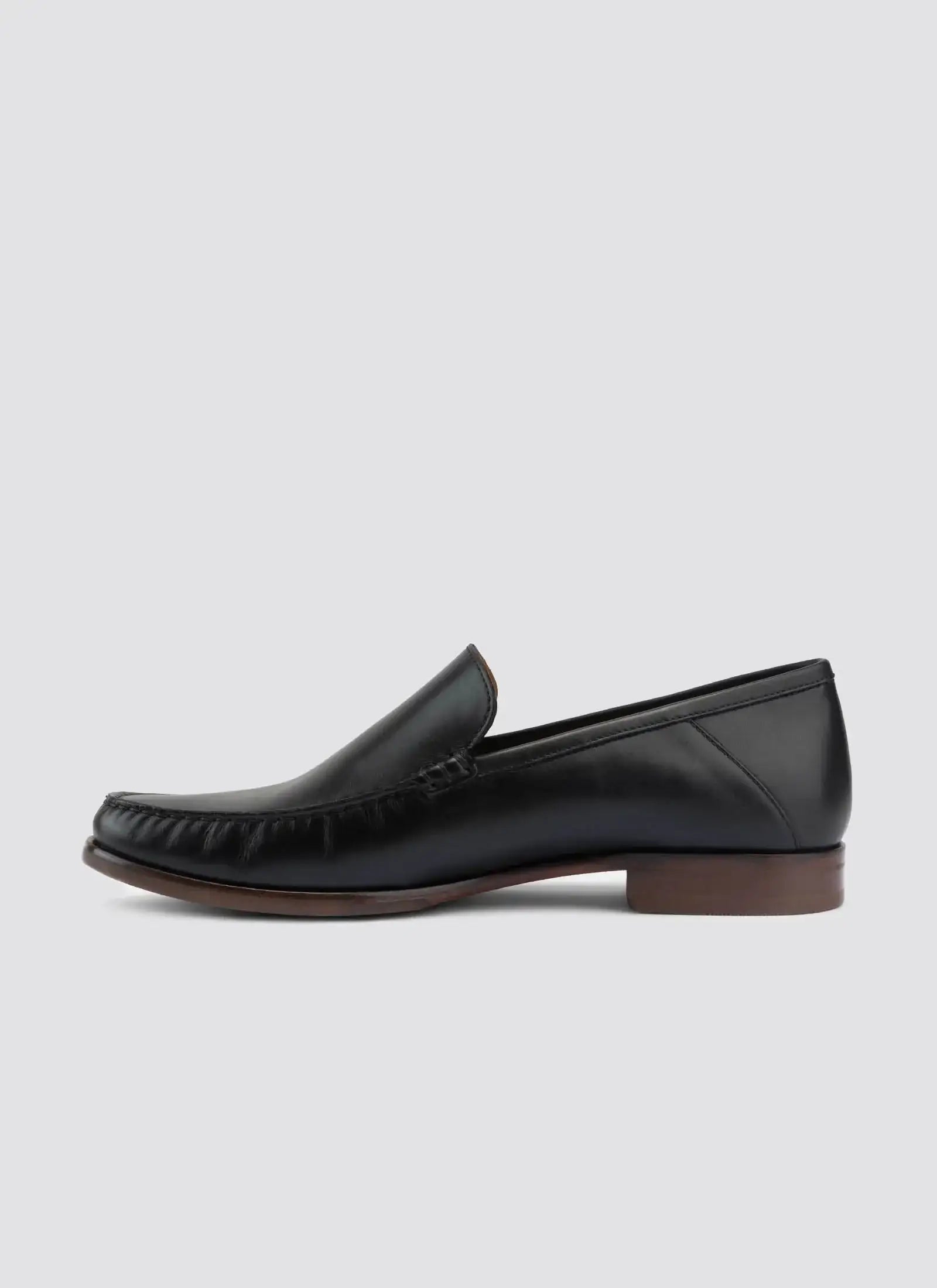Men's black leather loafer with brown sole, slip-on dress shoe on plain background