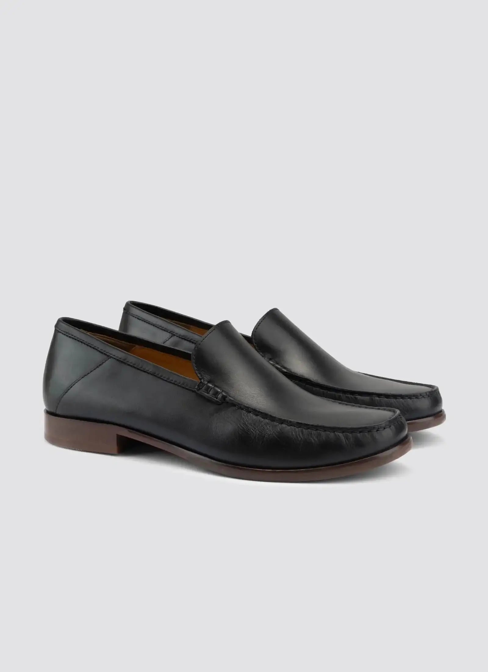 Men's black leather loafers with brown soles on a plain background #color_black