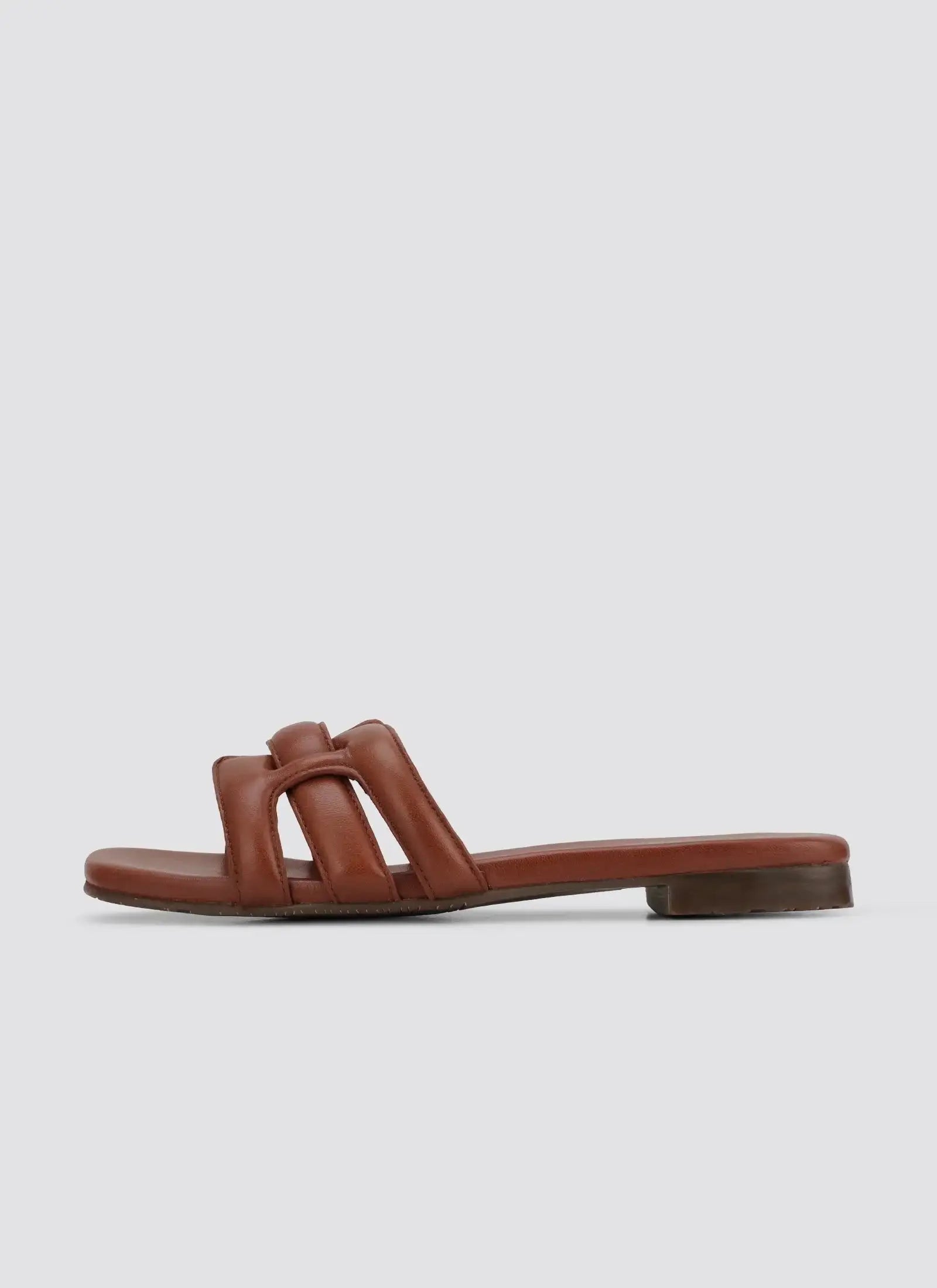 Tan brown flat leather slide sandal with cushioned straps on white background