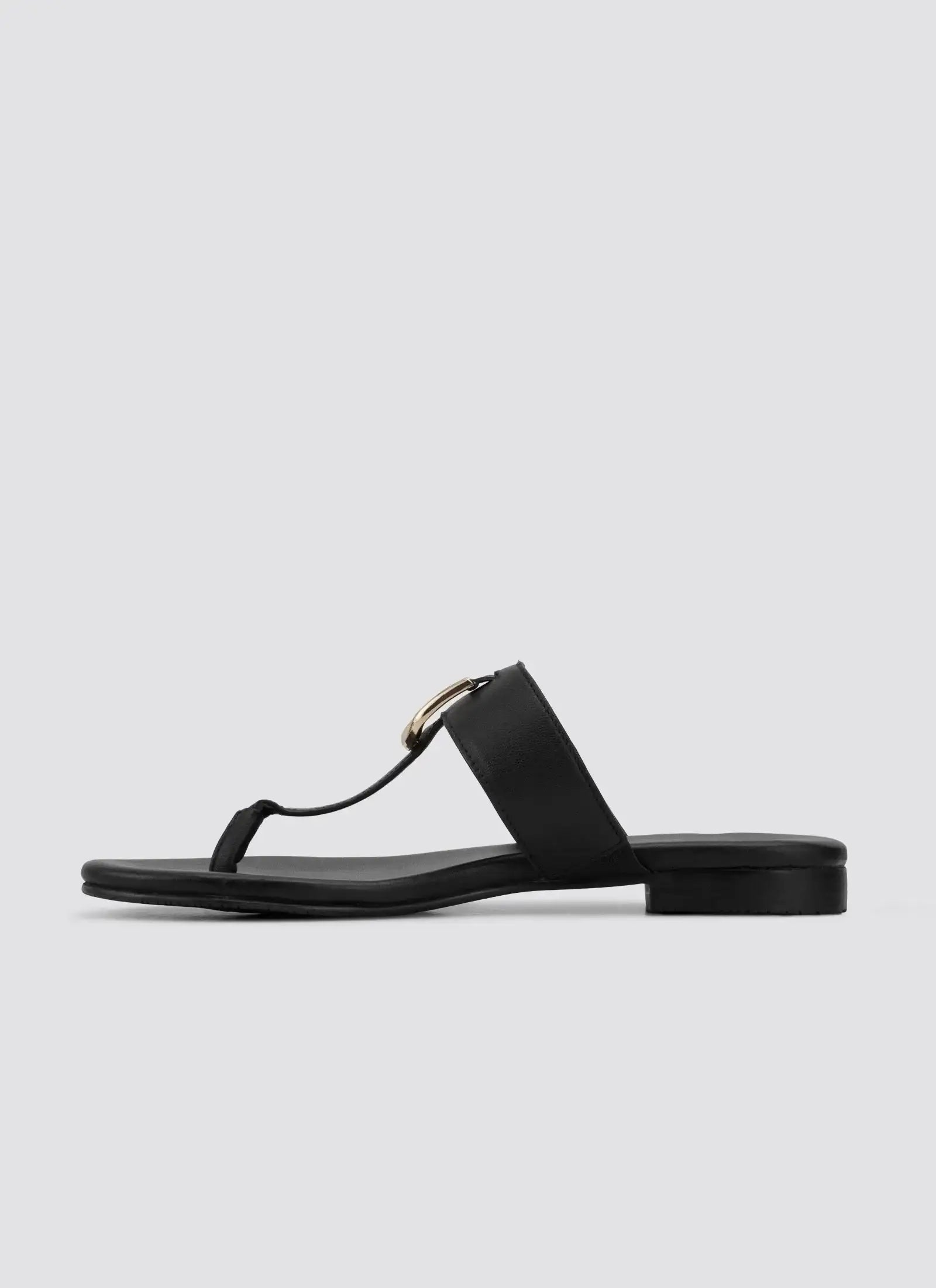 Black flat leather thong sandal with gold buckle detail for women on white background