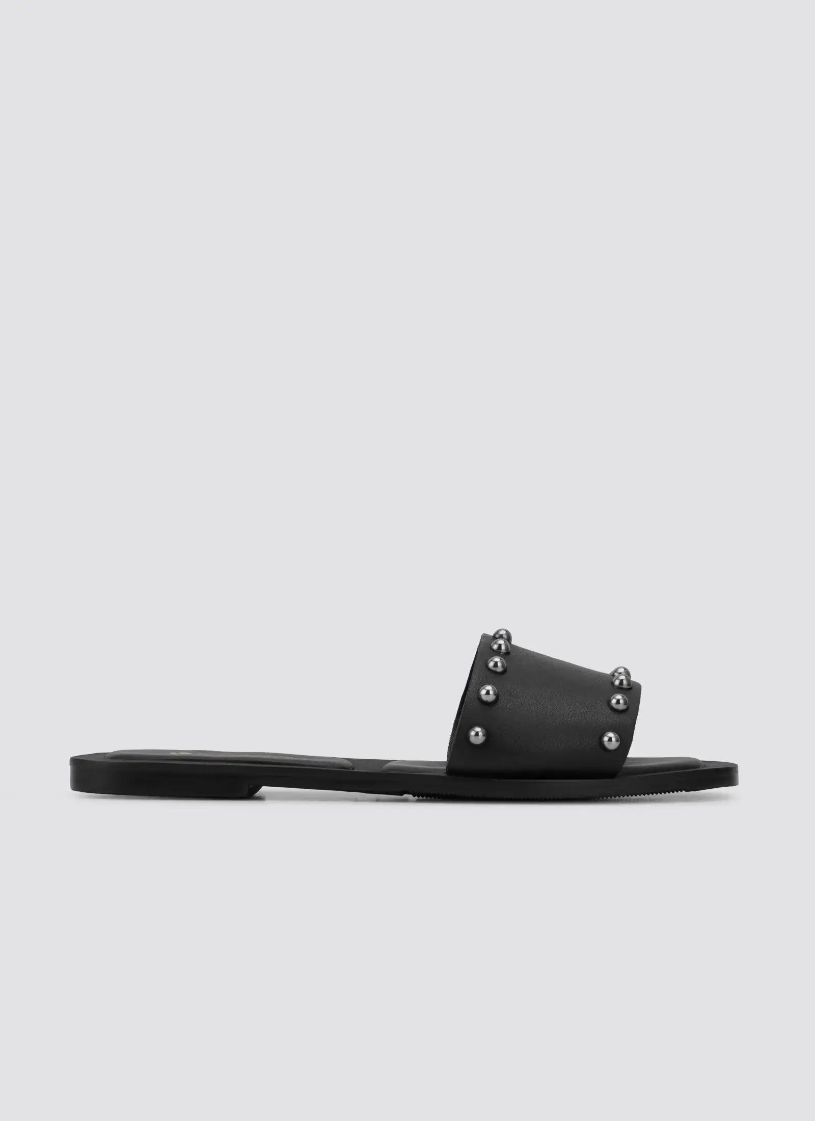 Black flat slide sandal with metal stud accents on the strap, side profile on white background