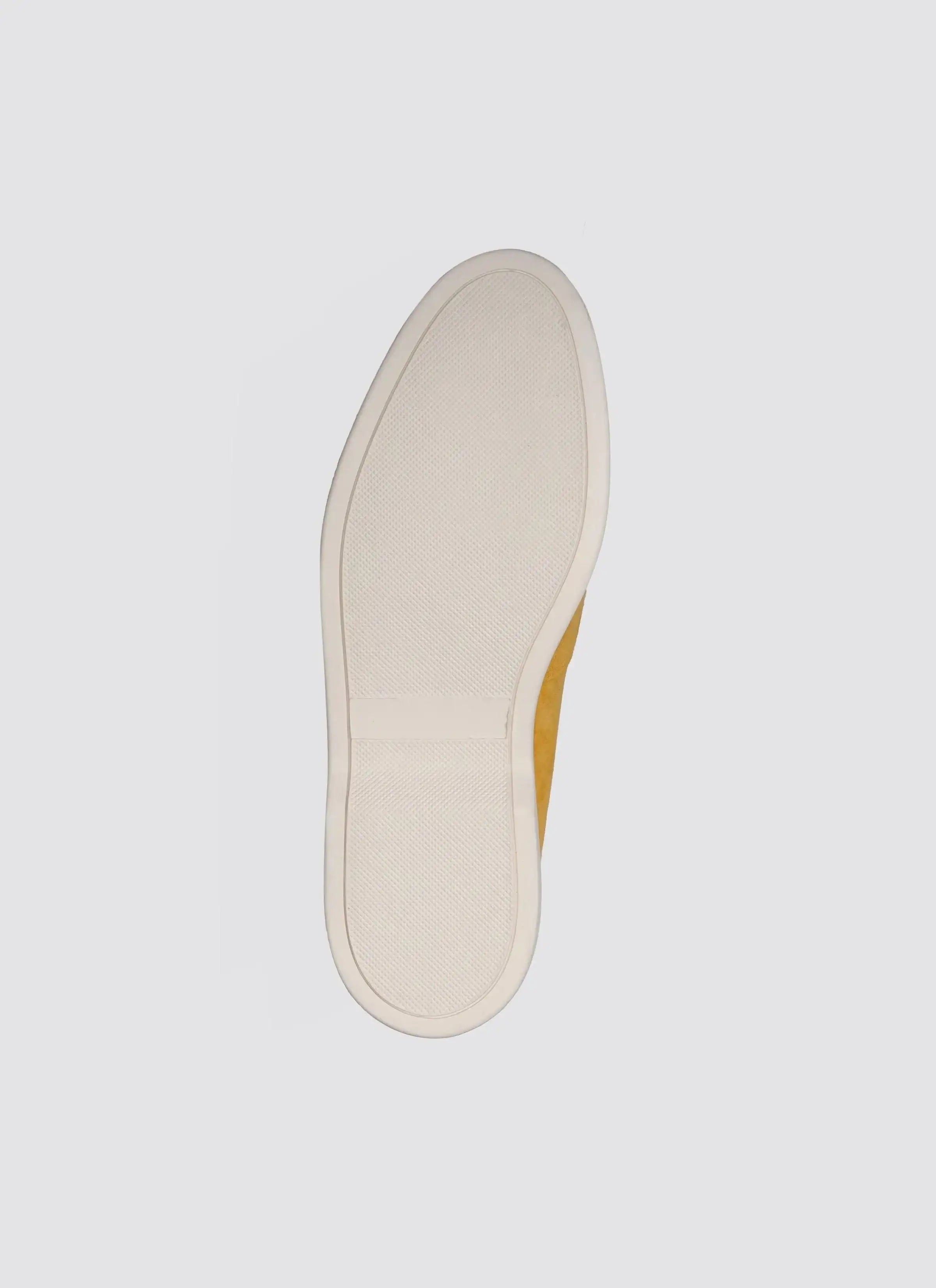 Mustard yellow shoe with textured white sole, viewed from the bottom on a plain background