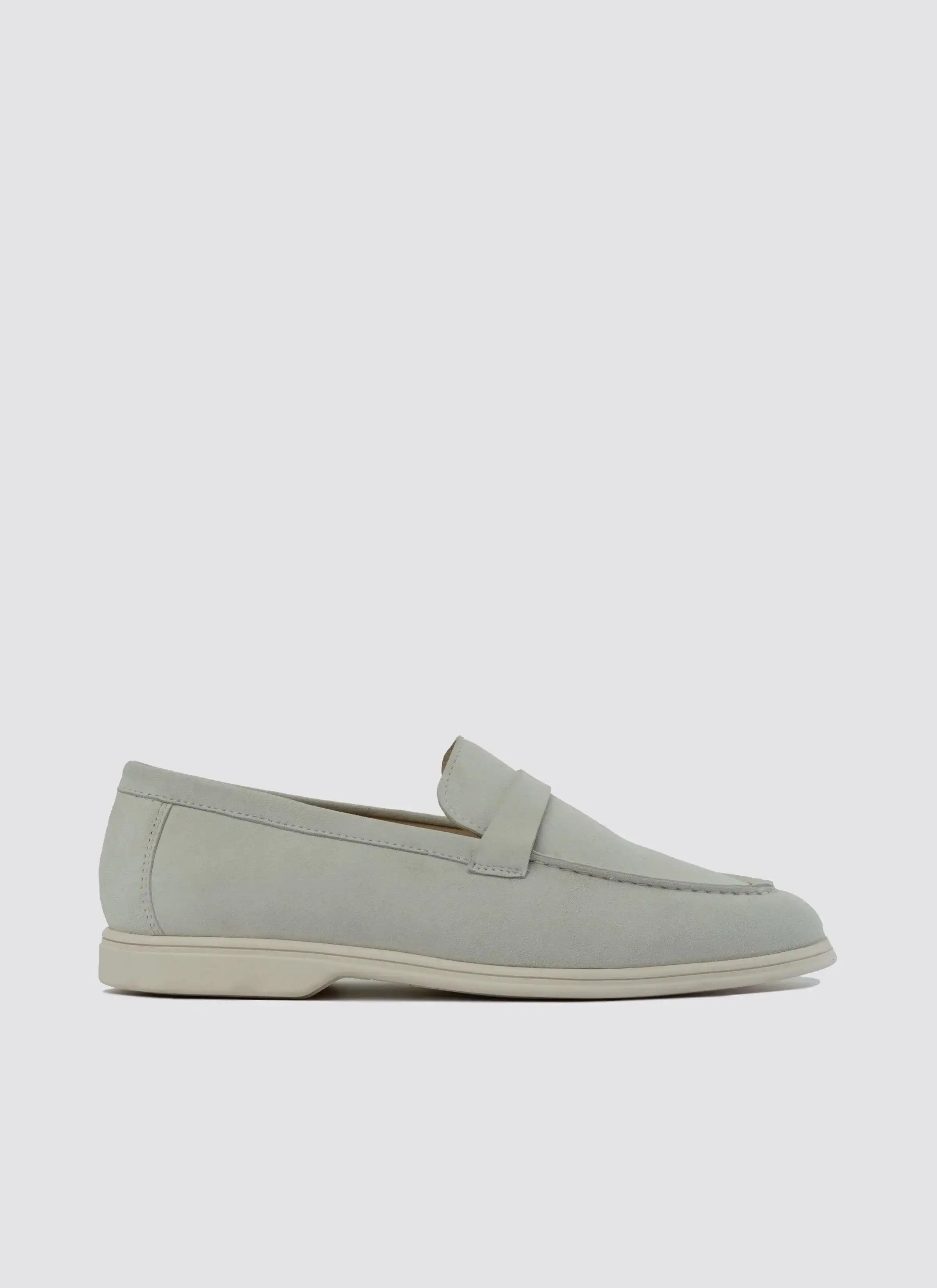 Off-white suede men's loafer with penny strap and low heel on plain background