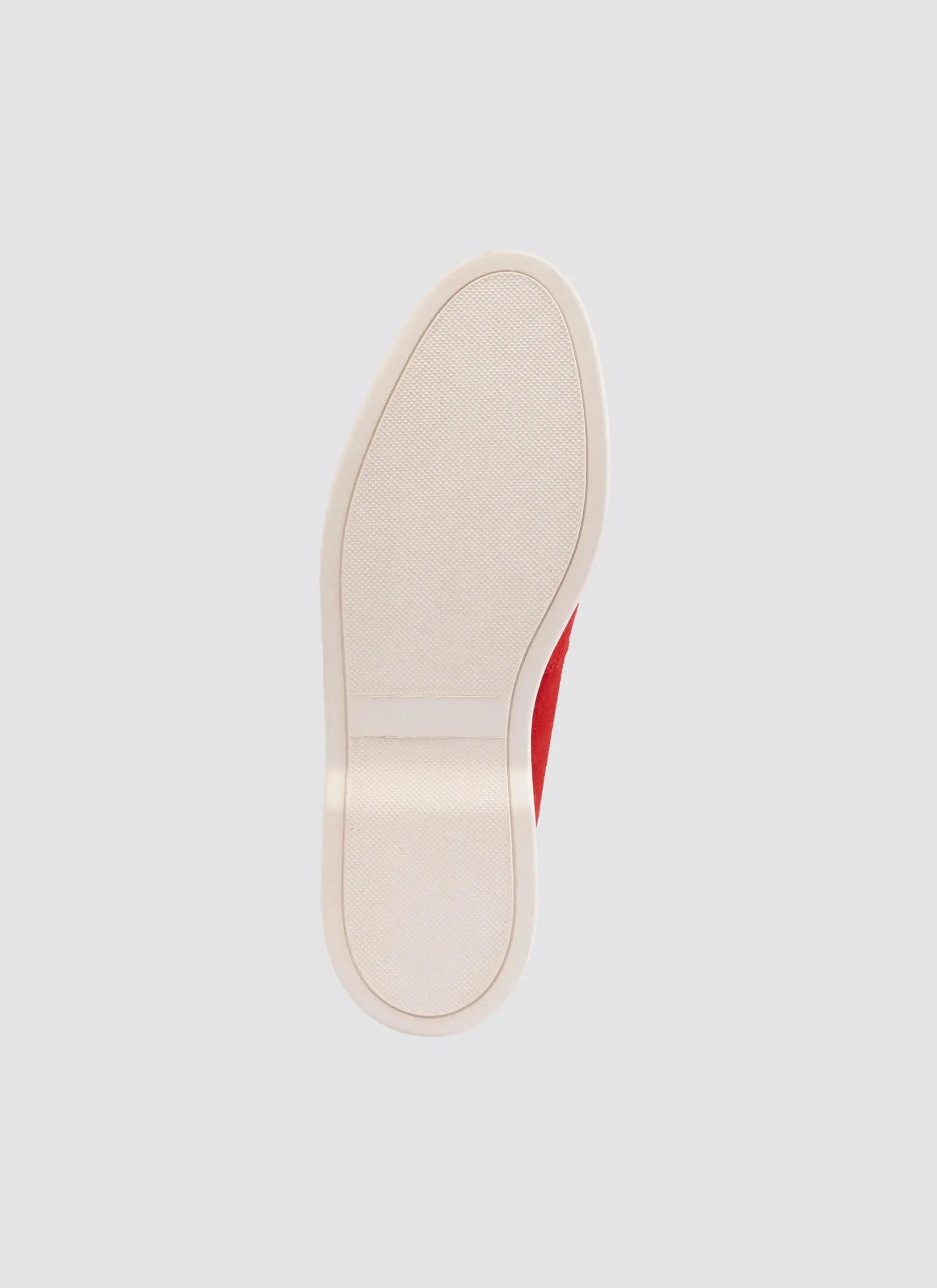 Close-up of red sneaker sole with textured white rubber outsole on light background