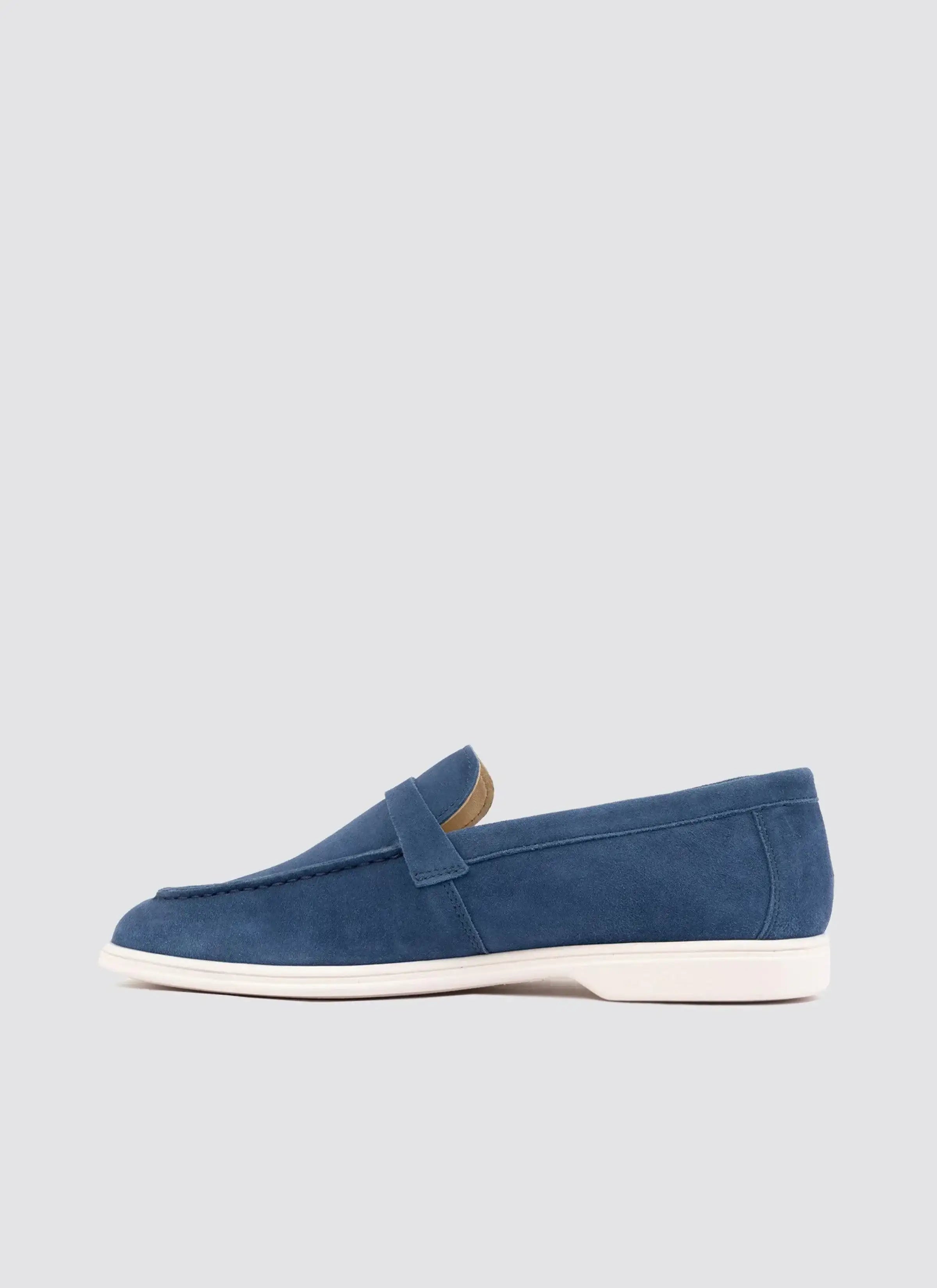 Navy blue suede men's loafer with white sole, side view, on light background