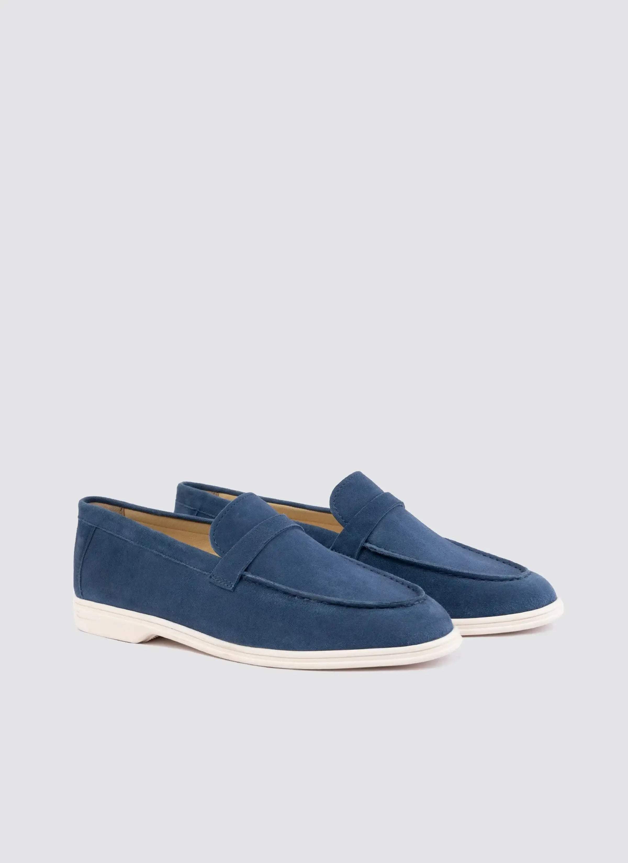 Men's navy blue suede loafers with white soles on a plain background