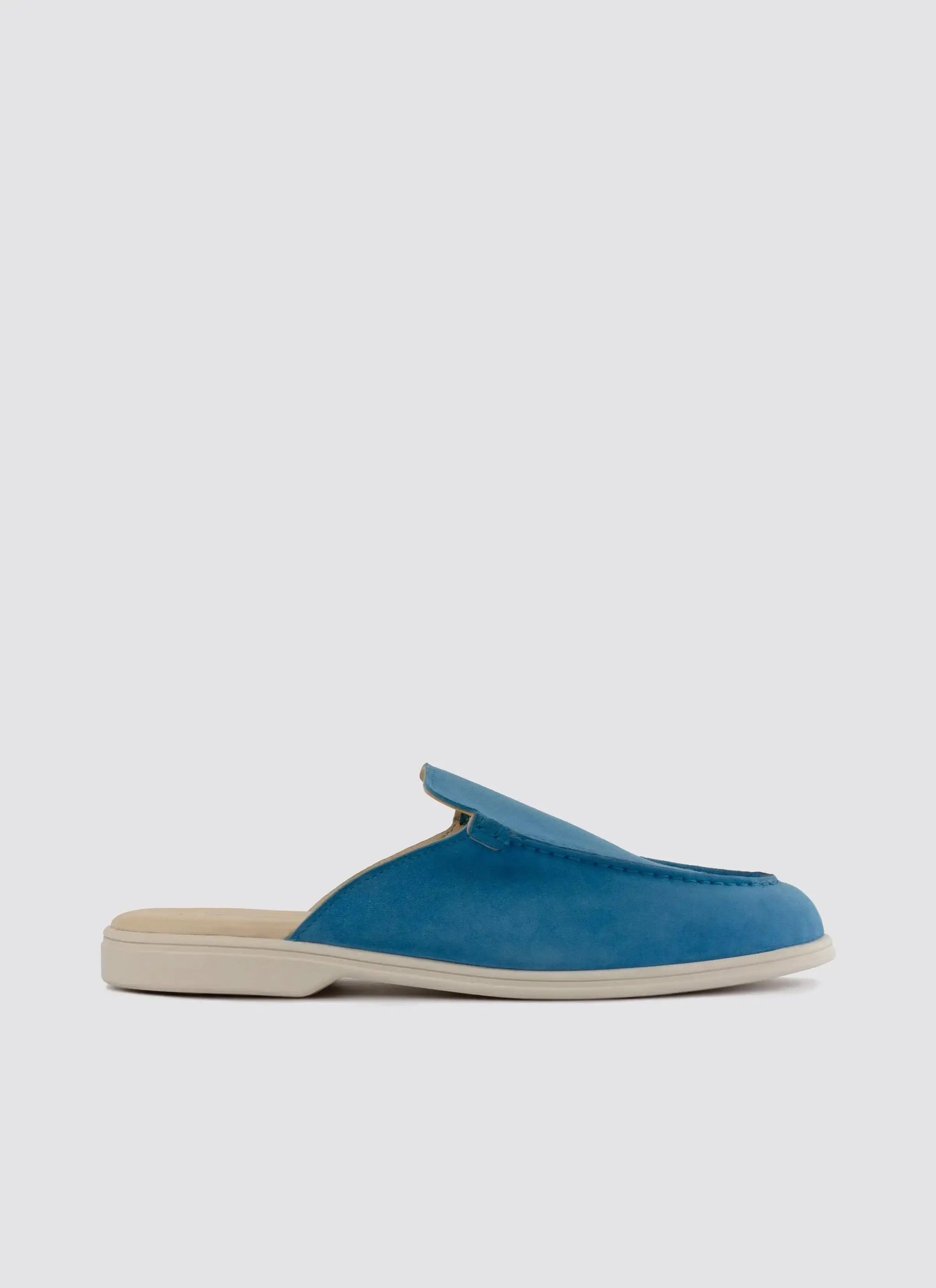 blue suede slip-on loafer mule with white sole on plain background