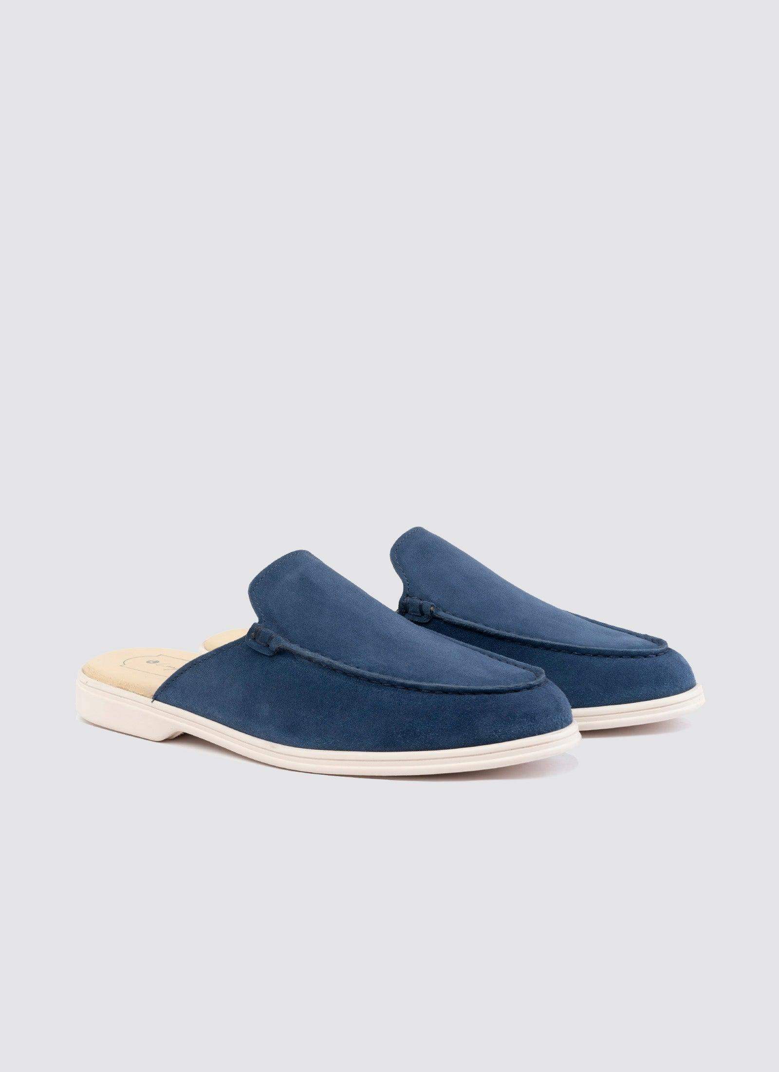 Men's navy blue suede slip-on loafers with white sole on a plain background