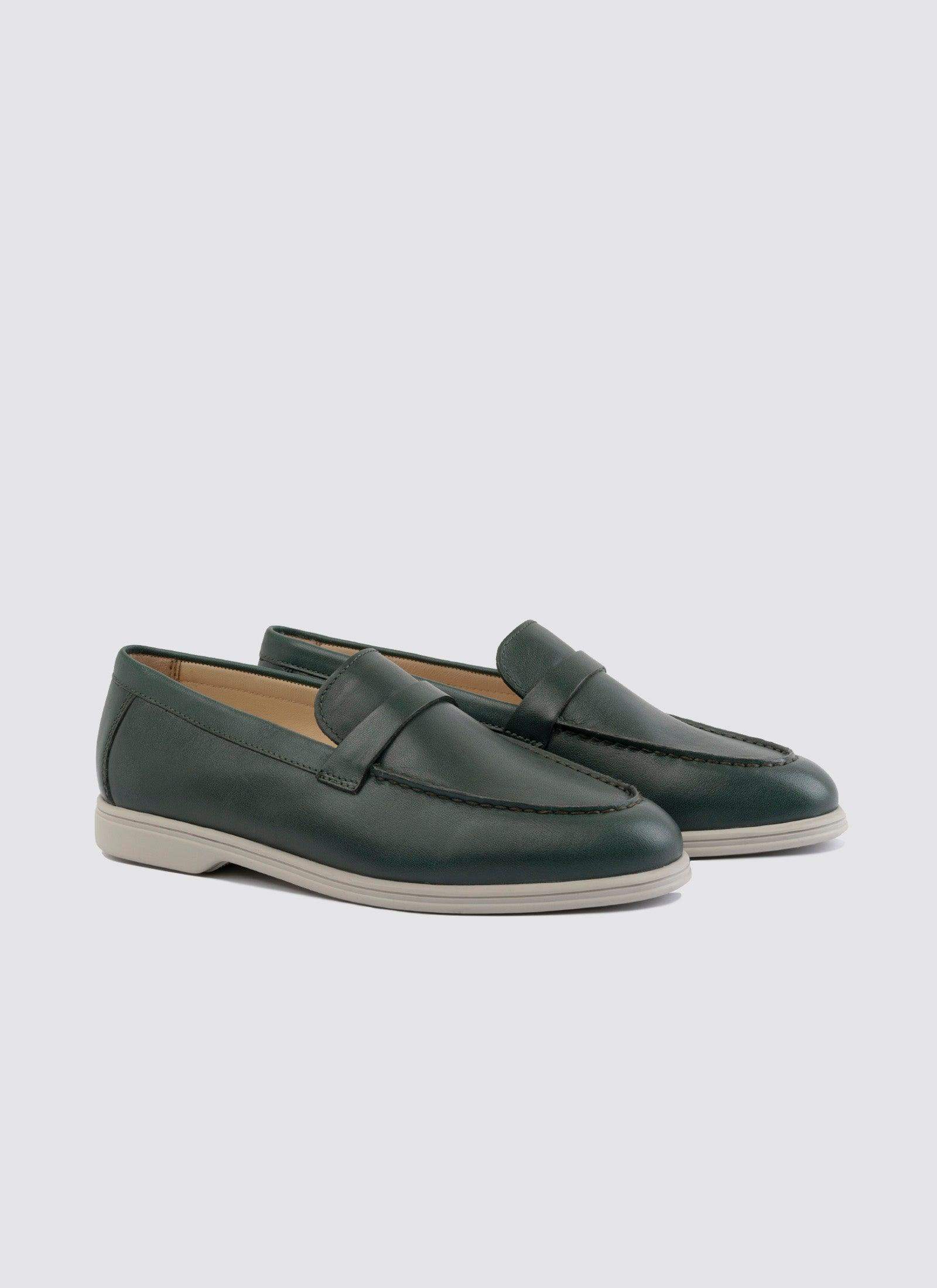 Forest green leather loafers for men with white rubber soles on a plain background