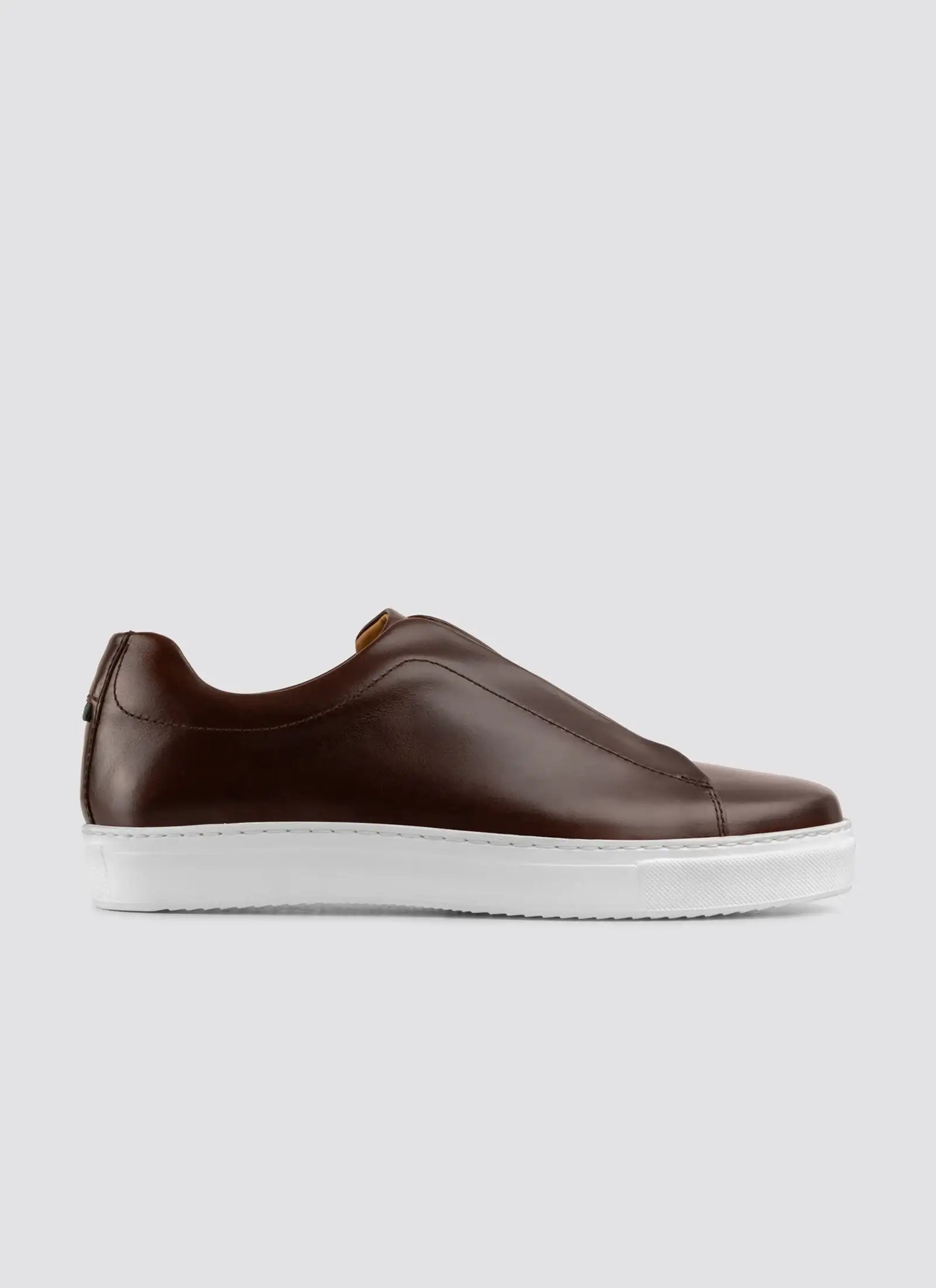 Brown slip-on shoe with white sole on a light gray background