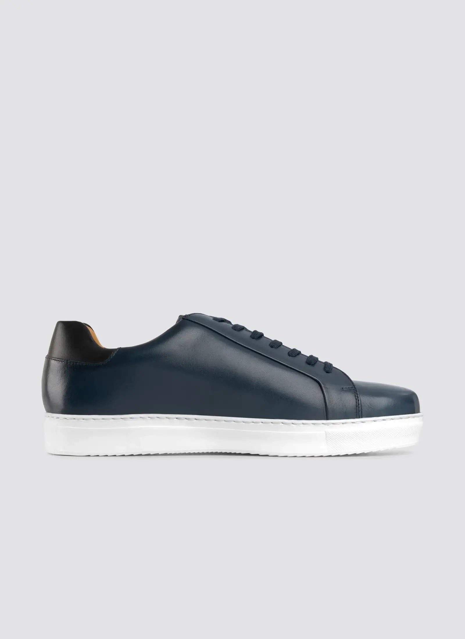 Men's navy blue leather sneaker with white sole and black heel accent on grey background