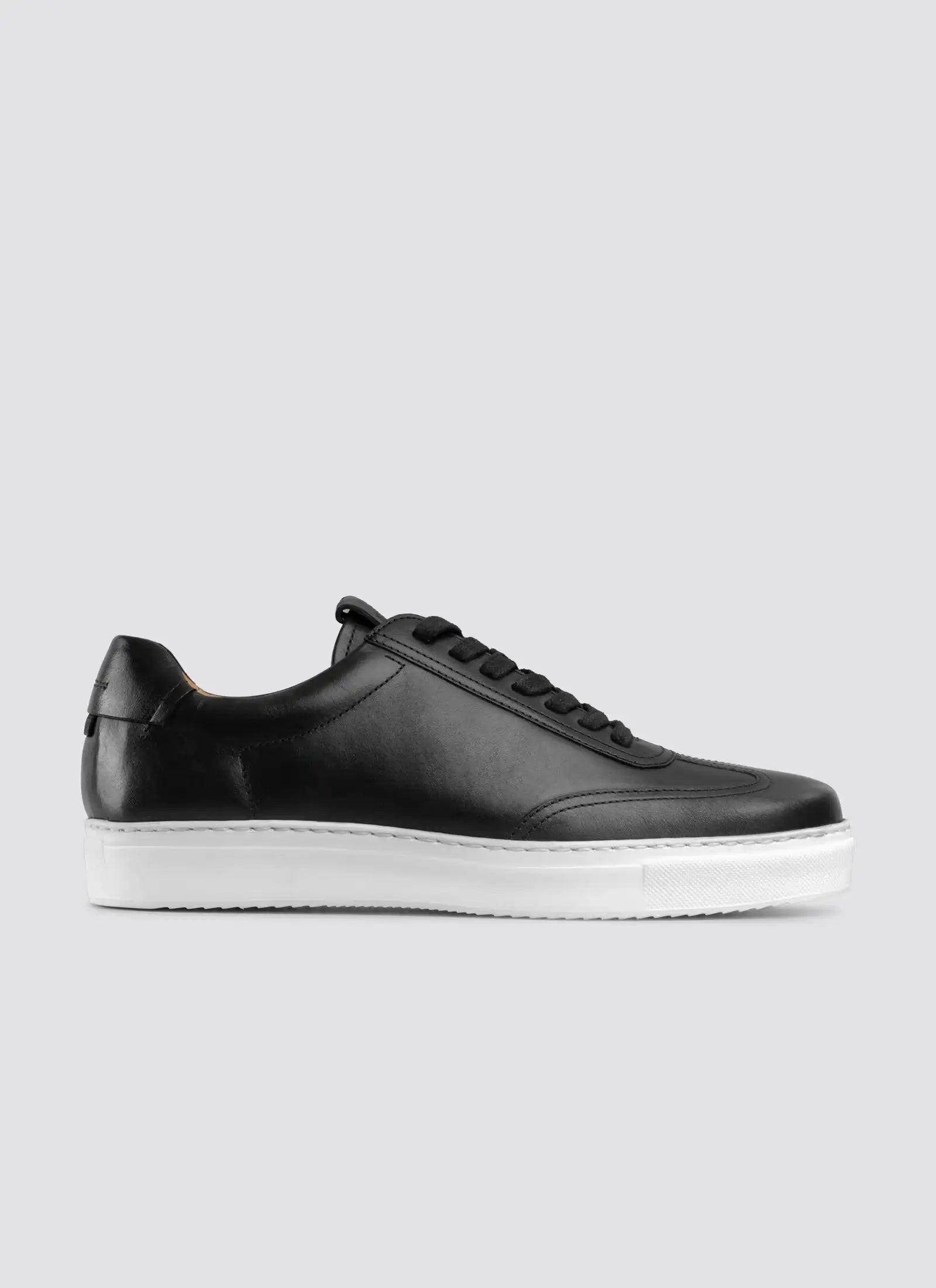 Black leather sneaker for men with white sole, side profile on a light background #color_black