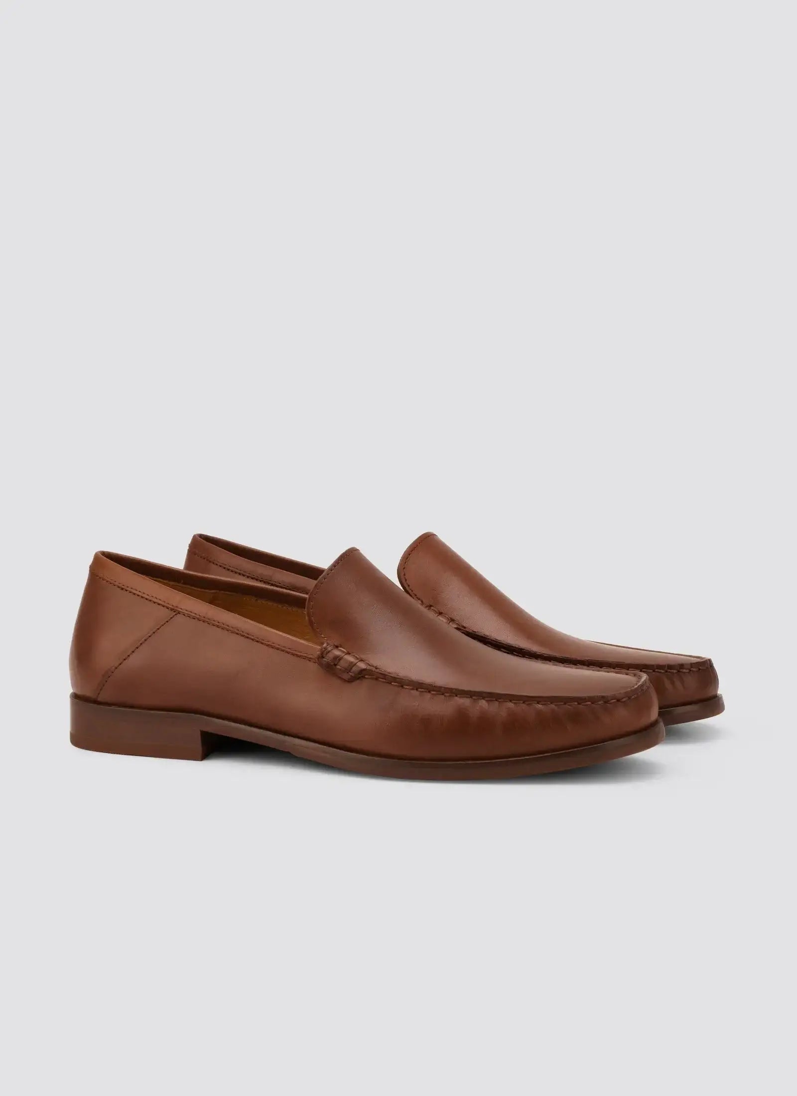 Men's brown leather loafers with a low heel on a plain background