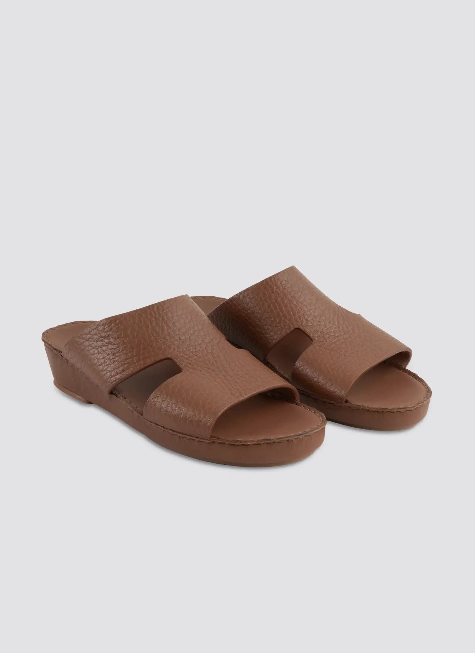 Pair of brown sandals on a light gray background