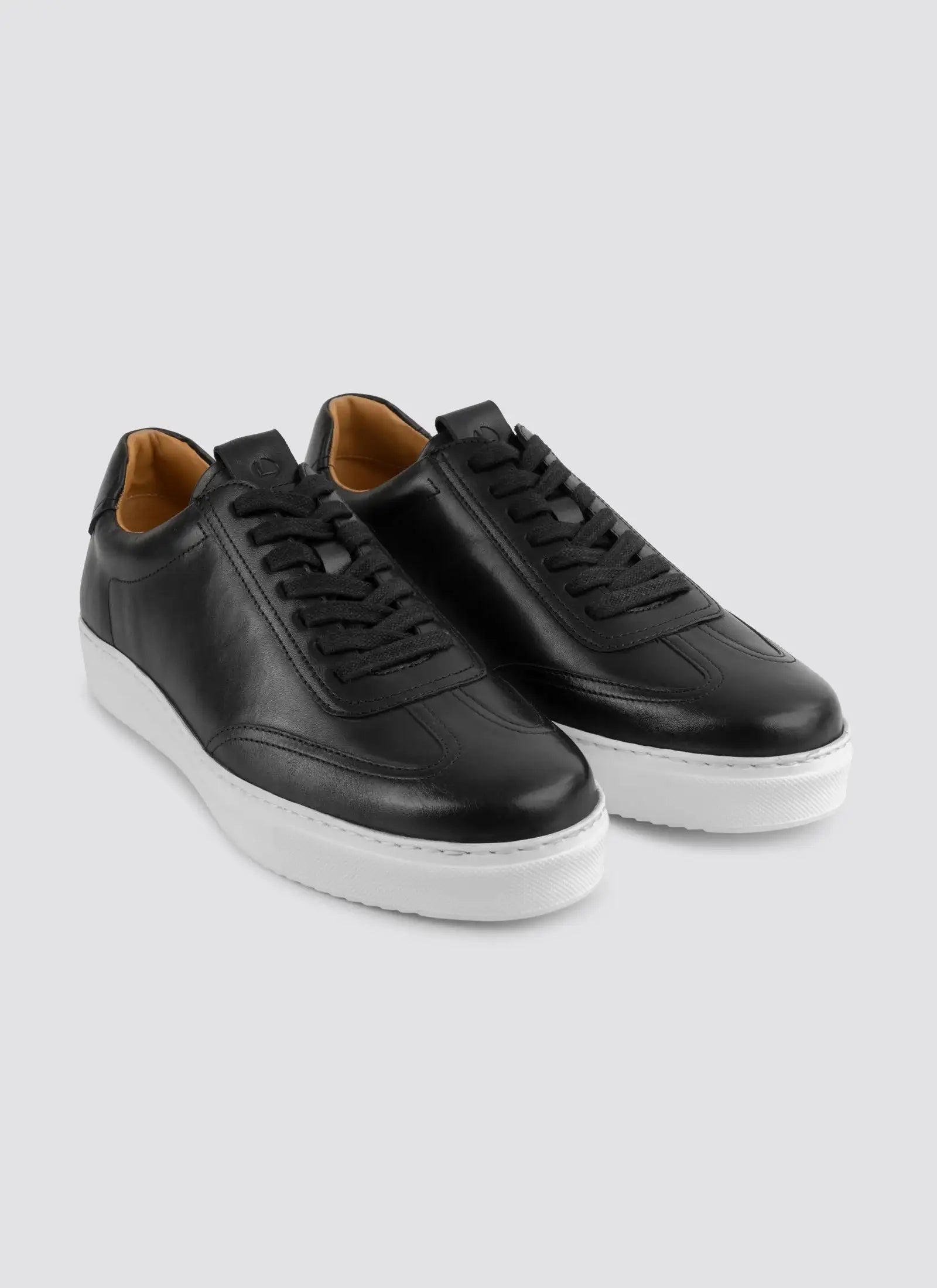 Black leather sneakers with white soles and black laces on a light background #color_black