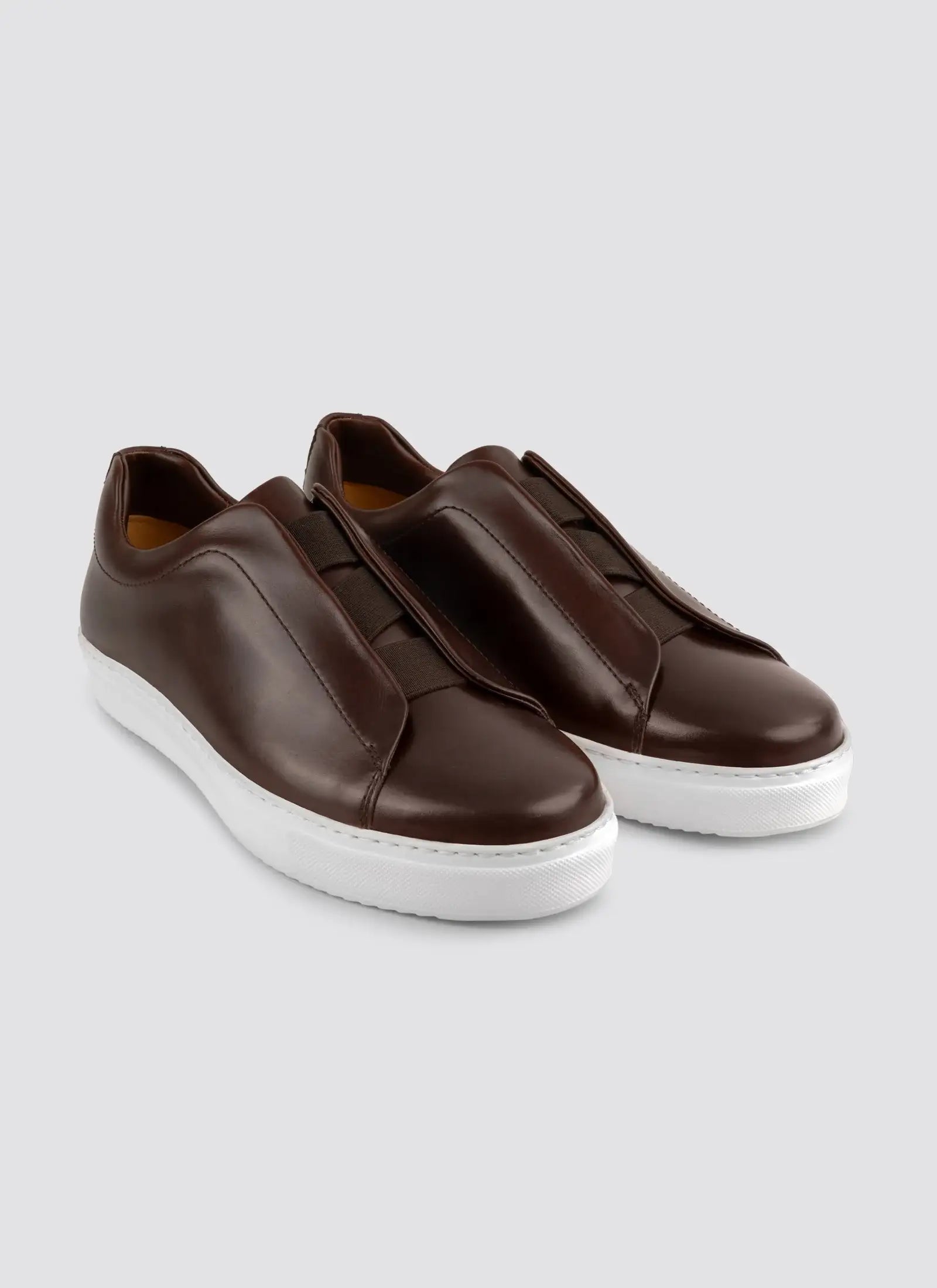 Pair of brown leather sneakers on a light gray background