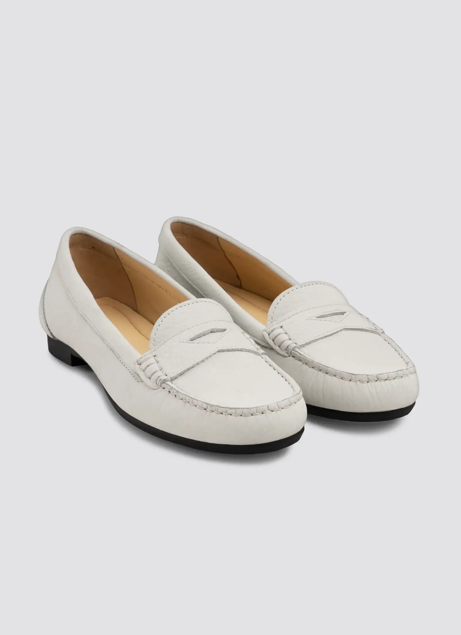 Pair of white loafers on a light gray background