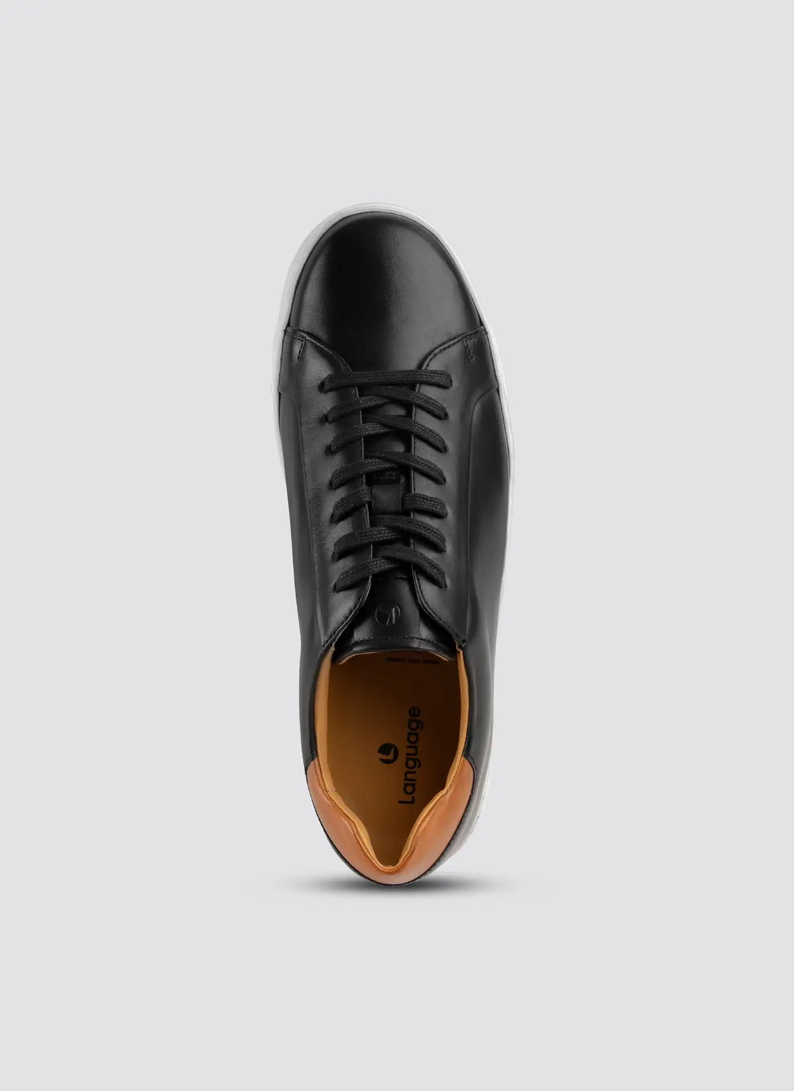 Black leather shoe with brown sole on a light gray background