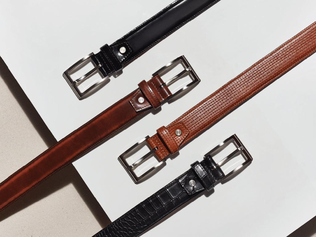 Three men's leather belts in black and brown with metallic buckles displayed on a white background.