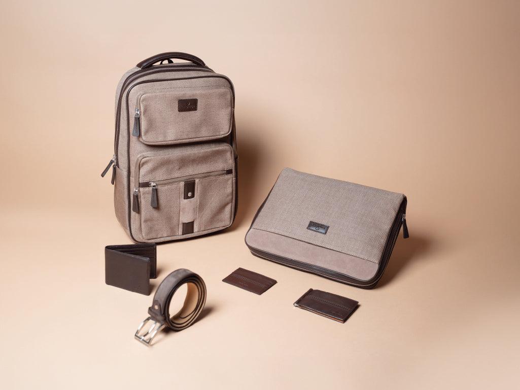 Beige canvas backpack, laptop sleeve, wallet, belt, and card holders for men on neutral background