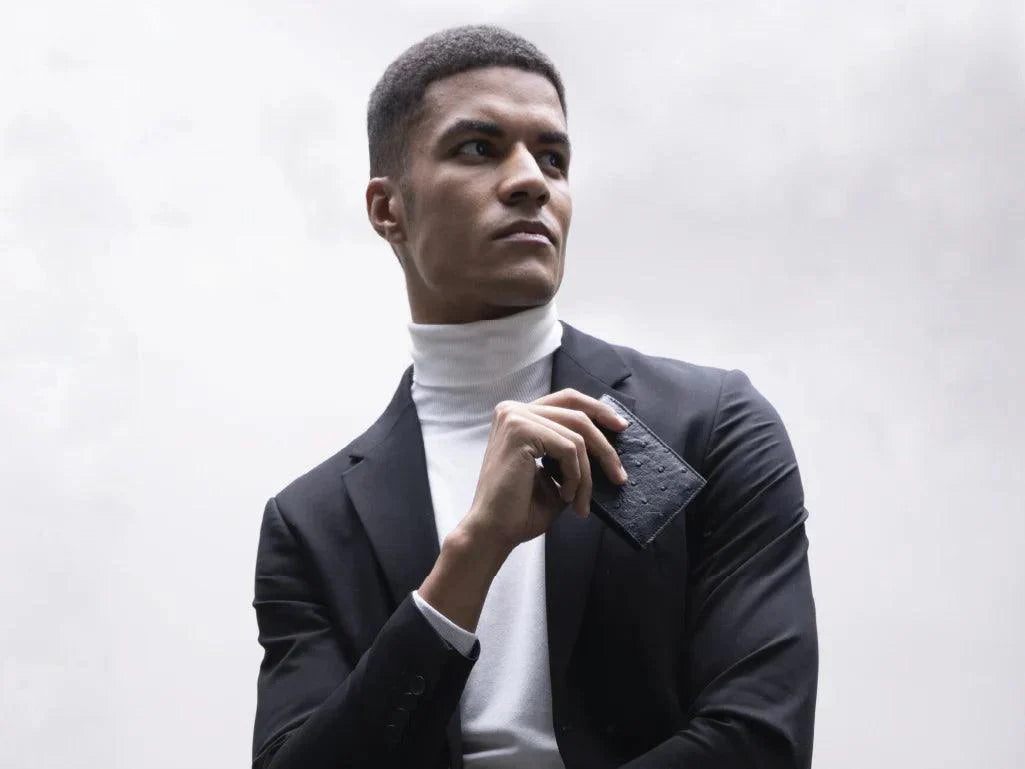 Stylish man in suit and turtleneck holding a black textured leather wallet