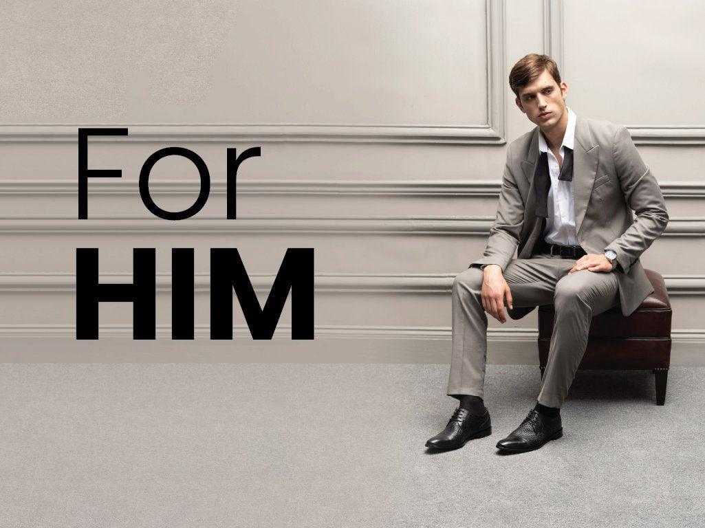 Man in grey suit and black dress shoes seated on bench, luxury men's footwear and fashion