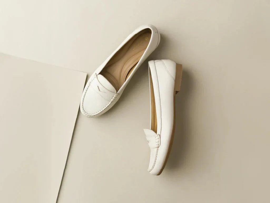 Pair of white leather loafers for women on a neutral background
