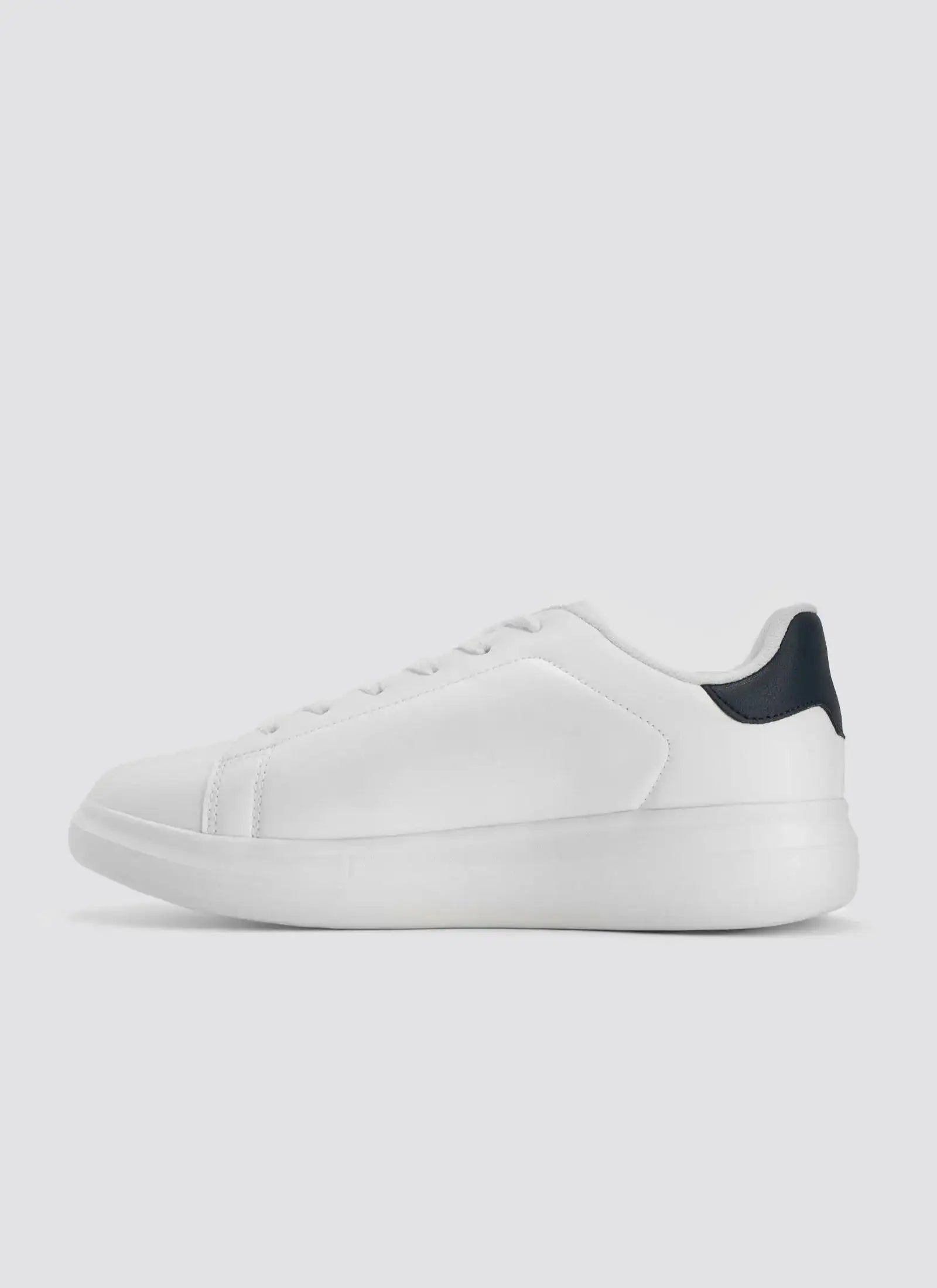 Minimalist white leather sneaker with black heel accent, side view, on white background 